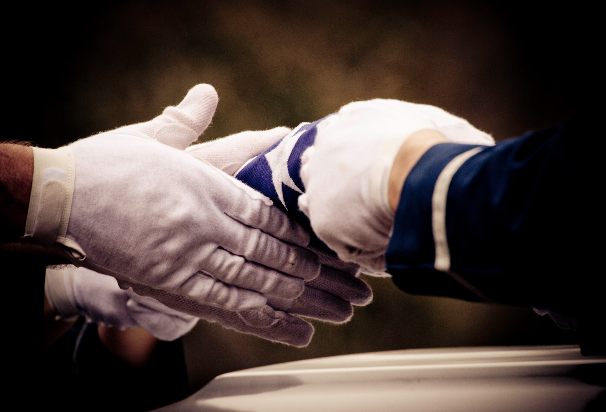 Members of the Eglin Air Force Base honor guard pass the American flag above the casket during a mock funeral as part of the honor guard graduation. Approximately 16 new Airmen graduated from the 80-plus-hour course.  Prior to the graduation, the Airmen perform a full honors, military funeral to include flag detail, the 21-gun salute, pall bearers and bugler for friends, family and unit commanders.  (U.S. Air Force photo/Samuel King Jr.)