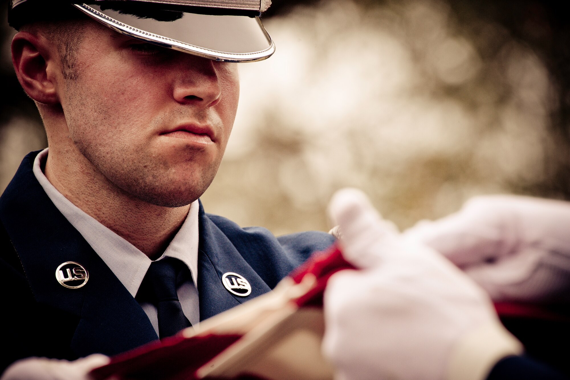 Senior Airman Chad Walker, of the Eglin Honor Guard, holds the American flag as it is folded above the casket during a mock funeral as part of the honor guard graduation. Approximately 16 new Airmen graduated from the 80-plus-hour course.  Prior to the graduation, the Airmen perform a full honors, military funeral to include flag detail, the 21-gun salute, pall bearers and bugler for friends, family and unit commanders.  (U.S. Air Force photo/Samuel King Jr.)