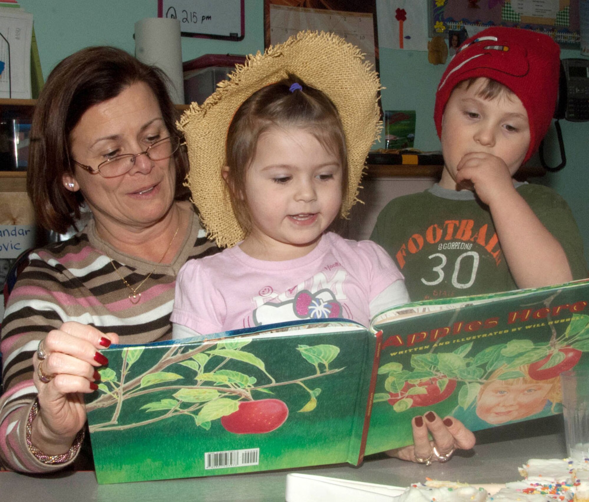 HANSCOM AIR FORCE BASE, Mass. - Nora Anderson (middle) and Aleksander Pavlovic read “Apples are Here” with Nora's grandmother, Mary Doster, during a Read Across America activity at the Child Development Center March 2. Read Across America is an annual reading motivation and awareness program that calls for children in every community to celebrate reading on the birthday of children’s author, Dr. Seuss. (U.S. Air Force photo by Linda LaBonte Britt)