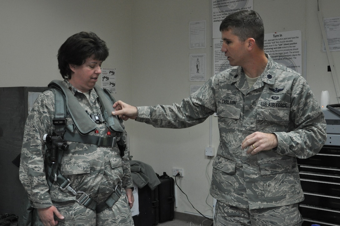SOUTHWEST ASIA -- Lt. Col. Paul K. Carlton III, 332nd Air Expeditionary Wing director of staff, shows Maj. Elisabeth Schmidt, 332nd AEW executive officer, the life preserver unit and other parts of a pilot’s parachute harness March 7, 2012 at an undisclosed location in Southwest Asia. Pilots use the harness to secure themselves into the aircraft prior to take-off. Carlton is deployed from Hill Air Force Base, Utah. Schmidt is deployed from the Montana Air National Guard and is a native of Great Falls, Mont. (U.S. Air Force photo by Senior Airman Melanie Holochwost)