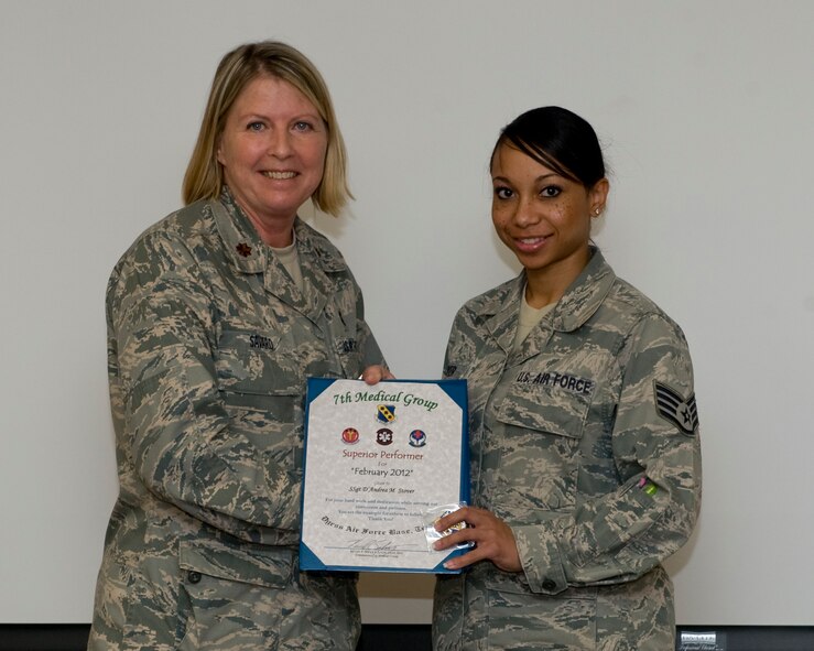 U.S. Air Force Maj. Denise Savard, 7th Medical Operations Squadron, presents Staff Sgt. D’Andrea Stover, 7th MDOS, with the February 7th Medical Group superior performer award, March 8, 2012, at Dyess Air Force Base, Texas. Every month each group selects a person or team who has shown superior performance to be recognized in front of wing leadership. (U.S. Air Force photo by Airman 1st Class Jonathan Stefanko/ Released)