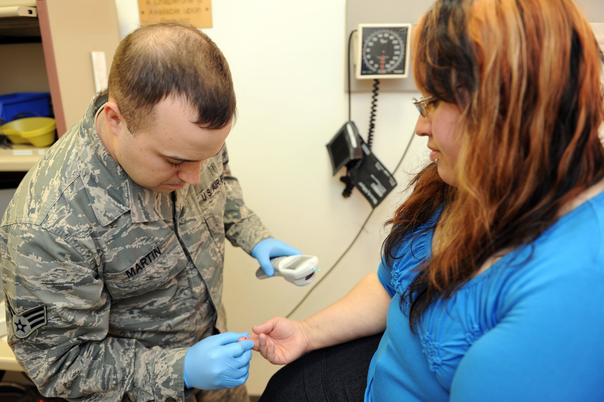 SPANGDAHLEM AIR BASE, Germany – Senior Airman Oliver Martin, 52nd Medical Operations Squadron ambulance service technician, checks Gabriela Francis, wife of Master Sgt. Brian Francis, 52nd Maintenance Operation Squadron, blood glucose level at Bldg. 137 here March 8. Ambulance techs provide initial medical response on Spangdahlem AB to support base response to in-flight and other mission related emergencies, as well as any other on-base incidents. The ambulance service provides emergency care for more than 8,400 Airmen, department of defense civilians, and their families. (U.S. Air Force photo by Senior Airman Christopher Toon/Released)