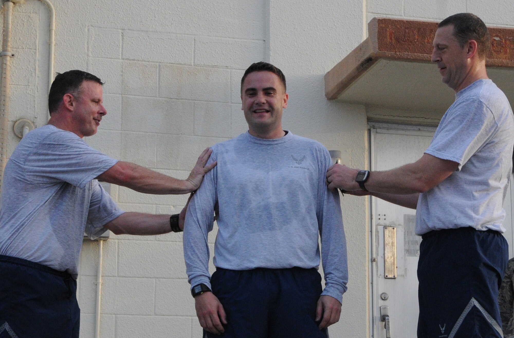KADENA AIR BASE, Japan -- Col. Brad Sullivan (right), the 353rd Special Operations Group commander, and Chief Master Sgt. Gregg Jones (left), the 353rd SOG command chief master sergeant, pins stripes Master Sgt. Claus Peris from the 353rd Special Operations Maintenance Squadron after a group run here March 8. Sergeant Peris was selected for promotion to senior master sergeant.