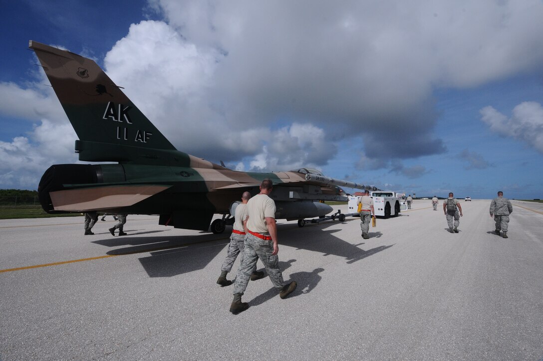 Maintainers from the 18th Aggressor Squadron walk beside the F-16 Fighting Falcon from Eielson Air Force base, Alaska as it is being towed to an area for maintenance. The aircraft made an emergency landing at Saipan International Airport, Feb. 21.(U.S. Air Force photo/Senior Airman Carlin Leslie)
