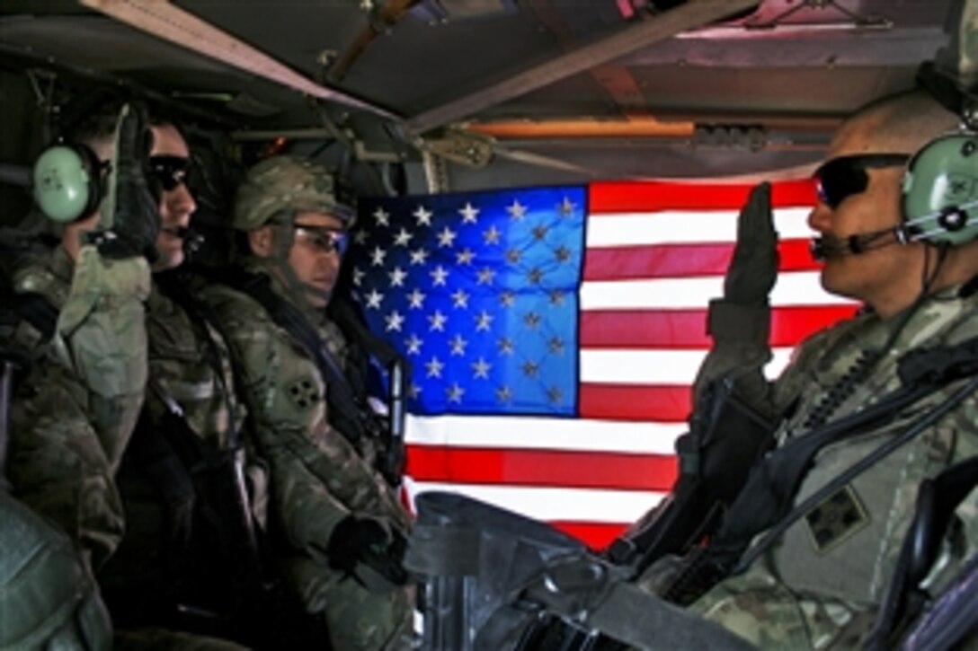 U.S. Army Chief Warrant Officer Rick Tyson swears in Spc. Rodger Beko during a re-enlistment in a Black Hawk helicopter hovering over Kandahar City, Afghanistan, March 7, 2012. Tyson is the brigade all source intelligence chief. Beko, an intelligence analyst with the 4th Infantry Division's 1st Squadron, 10th Cavalry Regiment, 2nd Brigade Combat Team, re-enlisted to serve three more years.
