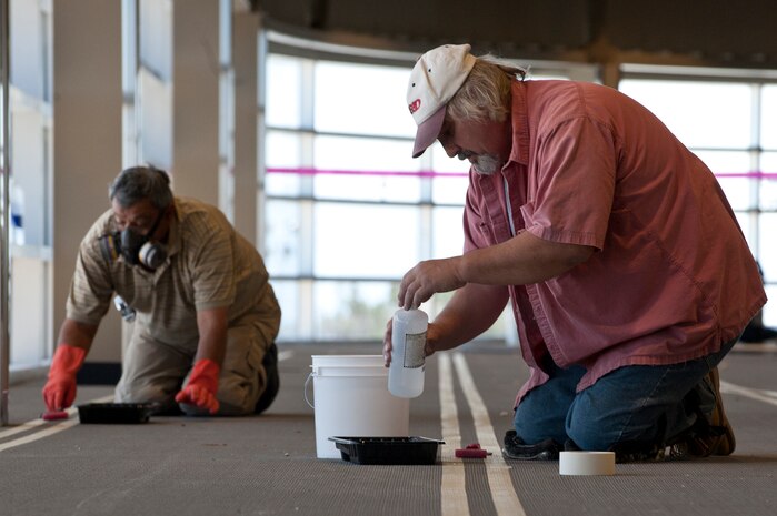 Sammy Carranza, Flooring Solutions Inc. foreman, and Mike Sisk,  Flooring Solutions Inc. journeyman, paint the track at the Warrior Fitness Center March 9, 2012, at Nellis Air Force Base, Nev. The Warrior Fitness Center is scheduled to open April 2012. (U.S. Air Force photo by Airman 1st Class Jason Couillard)