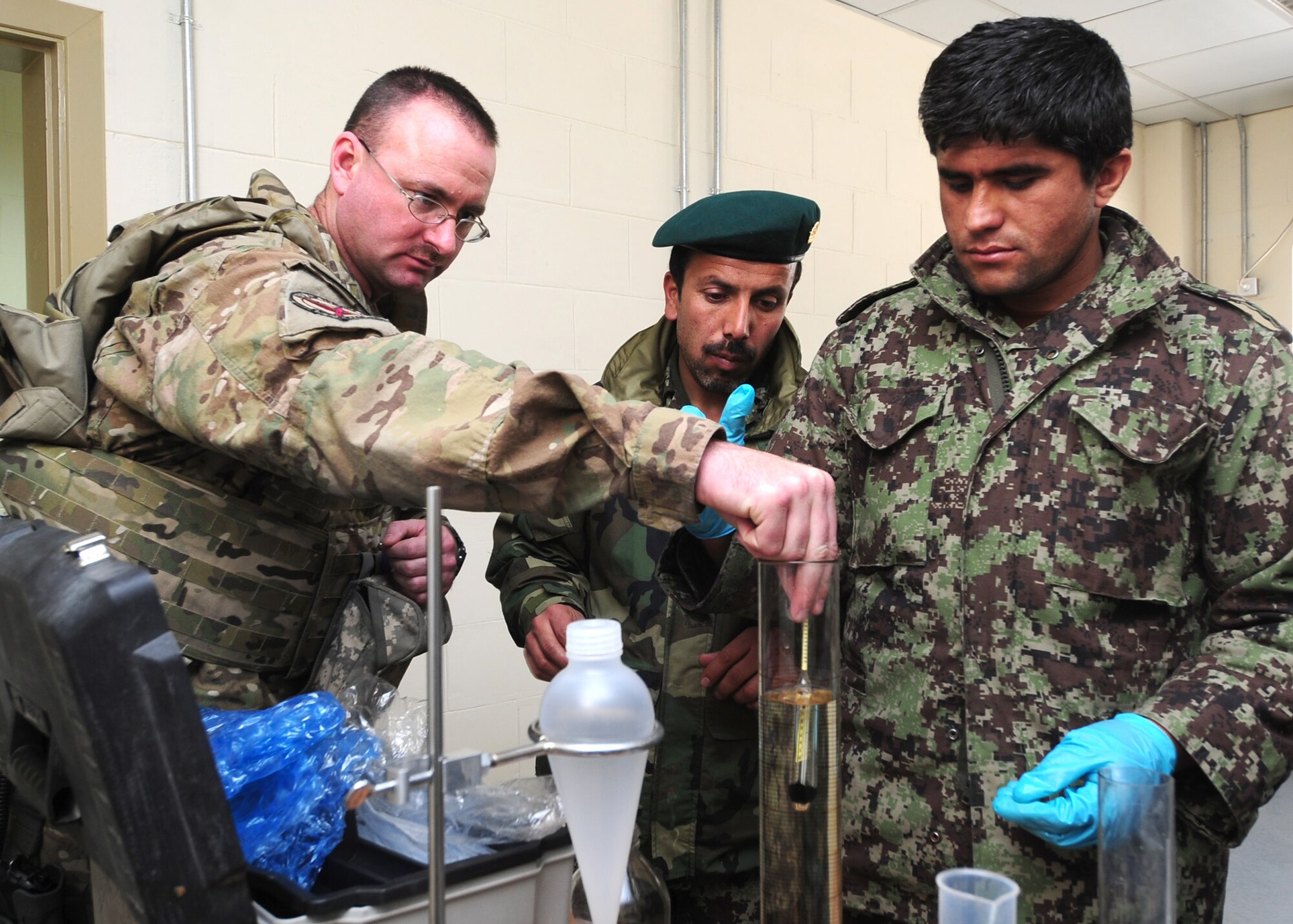 Master Sgt. Jeremiah Fentress, a fuels advisor with the 439th Air Expeditionary Advisory Squadron, explains to Afghan air force Lt. Mohammad Hamayoon and Sgt. Abdul Khalil, the proper way to take a temperature reading from a fuels sample during a basic fuels laboratory analysis training class at Kabul International Airport, March 5, 2012. In addition to analyzing fuels samples, students received specialized training needed to properly perform an American Petroleum Institute (API) density test, Fuels System Icing Inhibitor (FSII) test, Conductivity Unit (CU) test and an inline sample test. (U.S. Air Force photo by Staff Sgt. Nadine Y. Barclay)