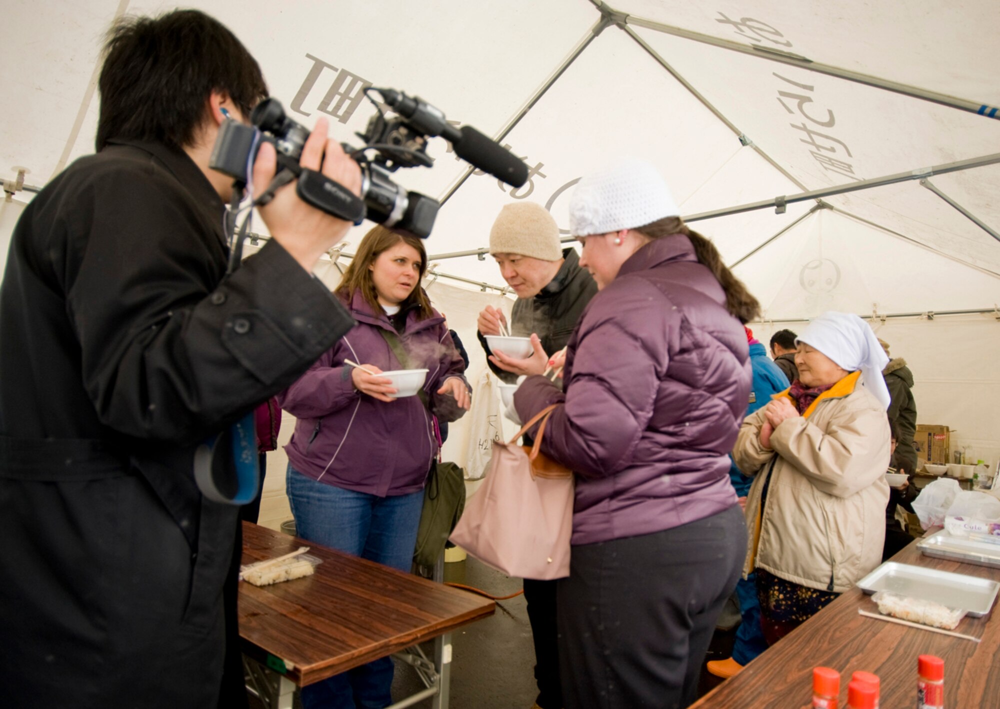 A Japanese news correspondent interviews Kathryn Lasky, Misawa Air Base American Red Cross volunteer, Shigenori Wada, 35th Civil Engineering Squadron, and Victory Harvey, Misawa Helps volunteer, during a Japan earthquake/tsunami remembrance ceremony at the Momoishi Port, Oirase Town, Japan March 11, 2012. Base community members, who helped with recovery efforts after Japan?s devastating earthquake, were able to meet family members from the Iwasaki Pork Farm nearly one year after the Misawa Helps/American Red Cross assisted with its clean up. (U.S. Air Force photo by Senior Airman Jess Lockoski)