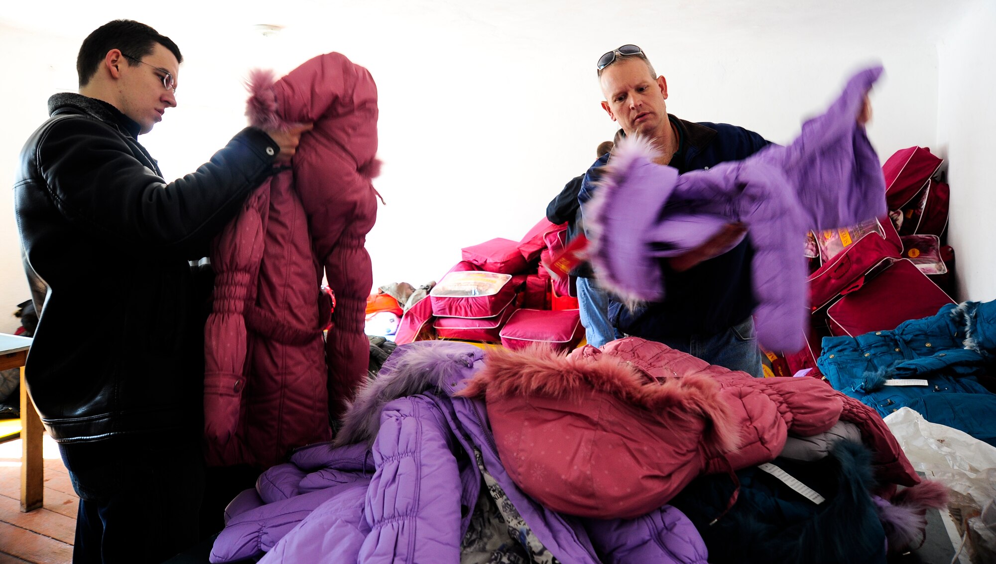 Staff Sgt. Igor Pogrebnyak (left) and Lt. Col. Adam Rutherford organize children's coats March 9, 2012, during an Operation Warm and Dry distribution at Kizil Arik village, Kyrgyzstan. Pogrebnyak, the Transit Center at Manas Theater Security Cooperation division host nation liaison NCO in charge, is deployed here from Creech Air Force Base, Nev. Rutherford is the TSC director and is deployed from Peterson AFB, Colo. (U.S. Air Force Photo/Staff Sgt. Angela Ruiz)