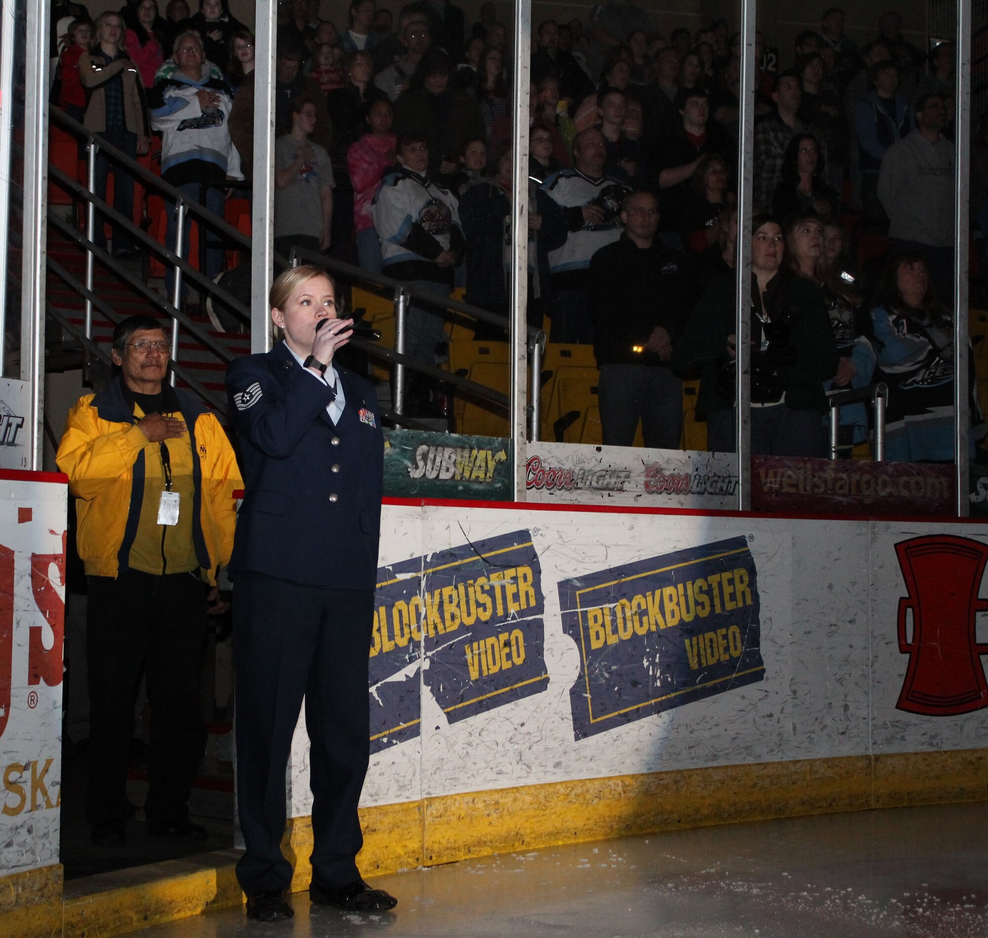Tech. Sgt. Heidi Dickinson, 477th Fighter Group, sings the National Anthem before the Alaska Aces hockey game March 10. In addition to the anthem singer, Lt. Col. David Piffarerio, 302nd Fighter Squadron commander, thanked spectators for their support of the Air Force Reserve in Alaska and dropped the puck before the start of the game. (U.S. Air Force/ Tech. Sgt. Dana Rosso) 