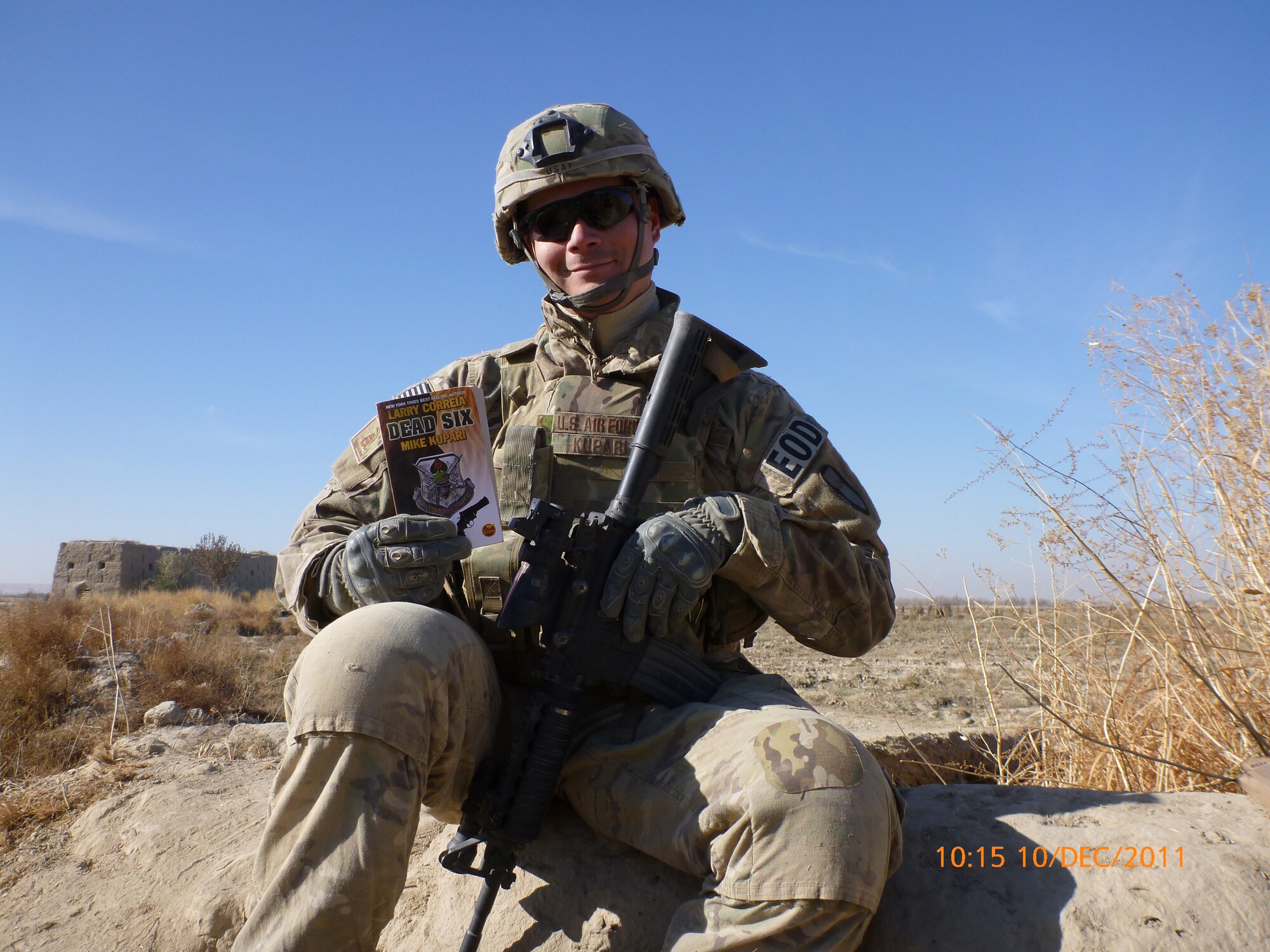 While deployed to Afghanistan in December 2011, Staff Sgt. Mike Kupari, 419th Explosive Ordnance Disposal, poses with a copy of the book he cowrote with best-selling author Larry Correia. (Courtesy photo)