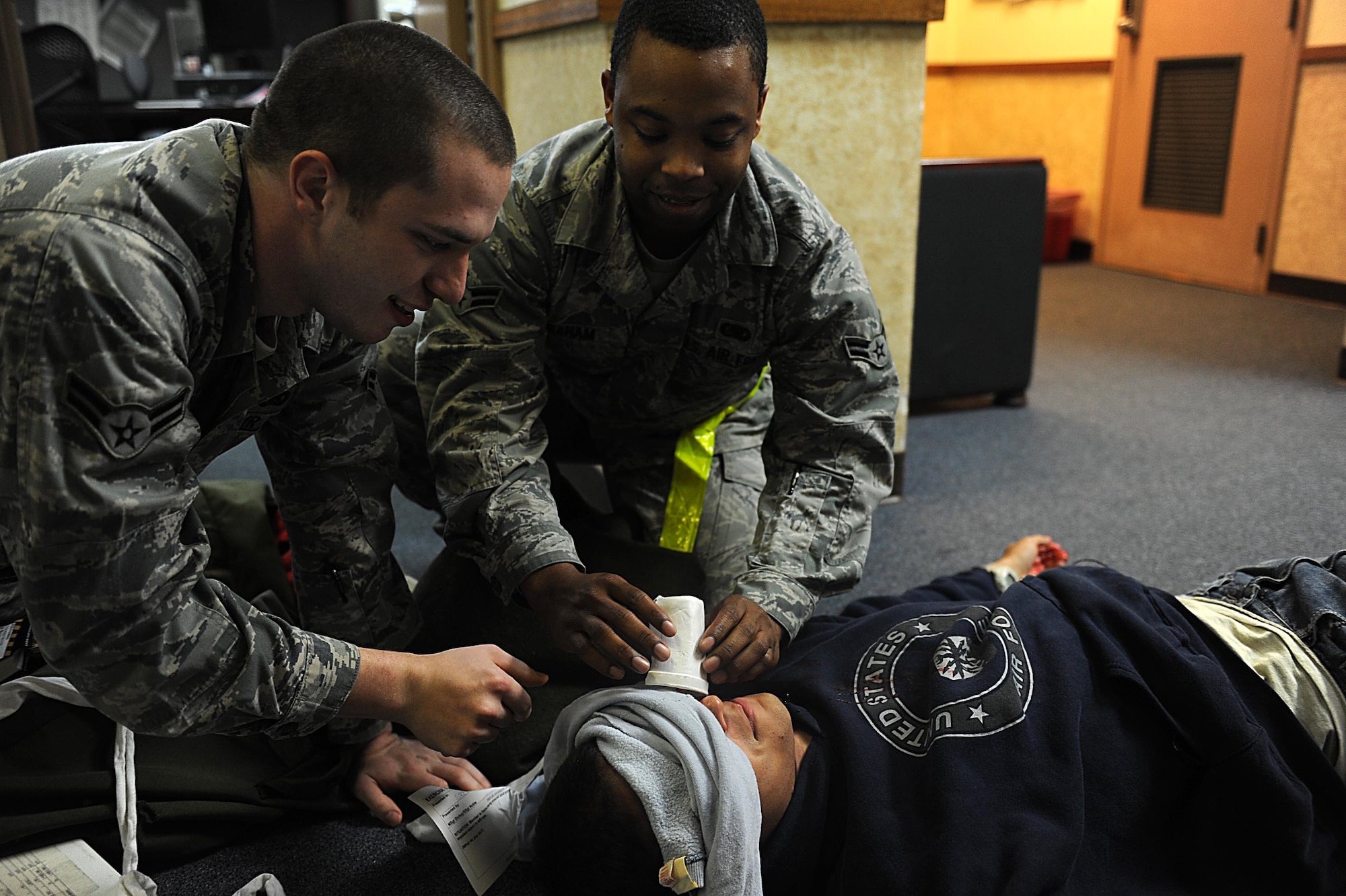 U.S. Air Force Airmen 1st Class Tyler Matthews and Charlie Graham, 18th Logistics Readiness Squadron, secure a moulaged object protruding from the eye of U.S. Air Force Senior Airman Anthony Augustine, 961st Airborne Air Control Squadron, so it won't cause anymore damage during training on Kadena Air Base, March 12, 2012. Kadena is participating in Beverly High 12-3, a local operational readiness exercise, which prepares Airmen for real world contingencies. (U.S. Air Force photo by Airman 1st Class Brooke P. Beers/Released)