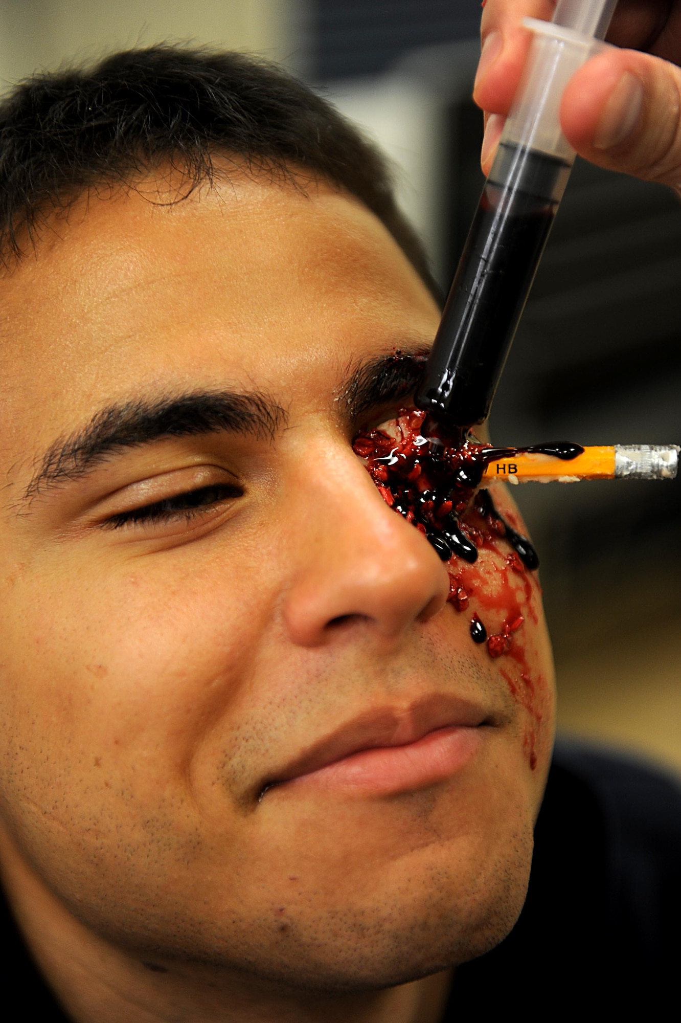 U.S. Air Force Senior Airman Anthony Augustine, member of the 961st Airborn Air Control Squadron, has more fake blood applied to his pencil wound during a simulated training exercise on Kadena Air Base, March 12, 2012. Kadena is participating in a local operational readiness exercise to prepare Shogun Airmen for possible real world contingencies in a safe environment. (U.S. Air Force photo by Airman 1st Class Brooke P. Beers/Released)
