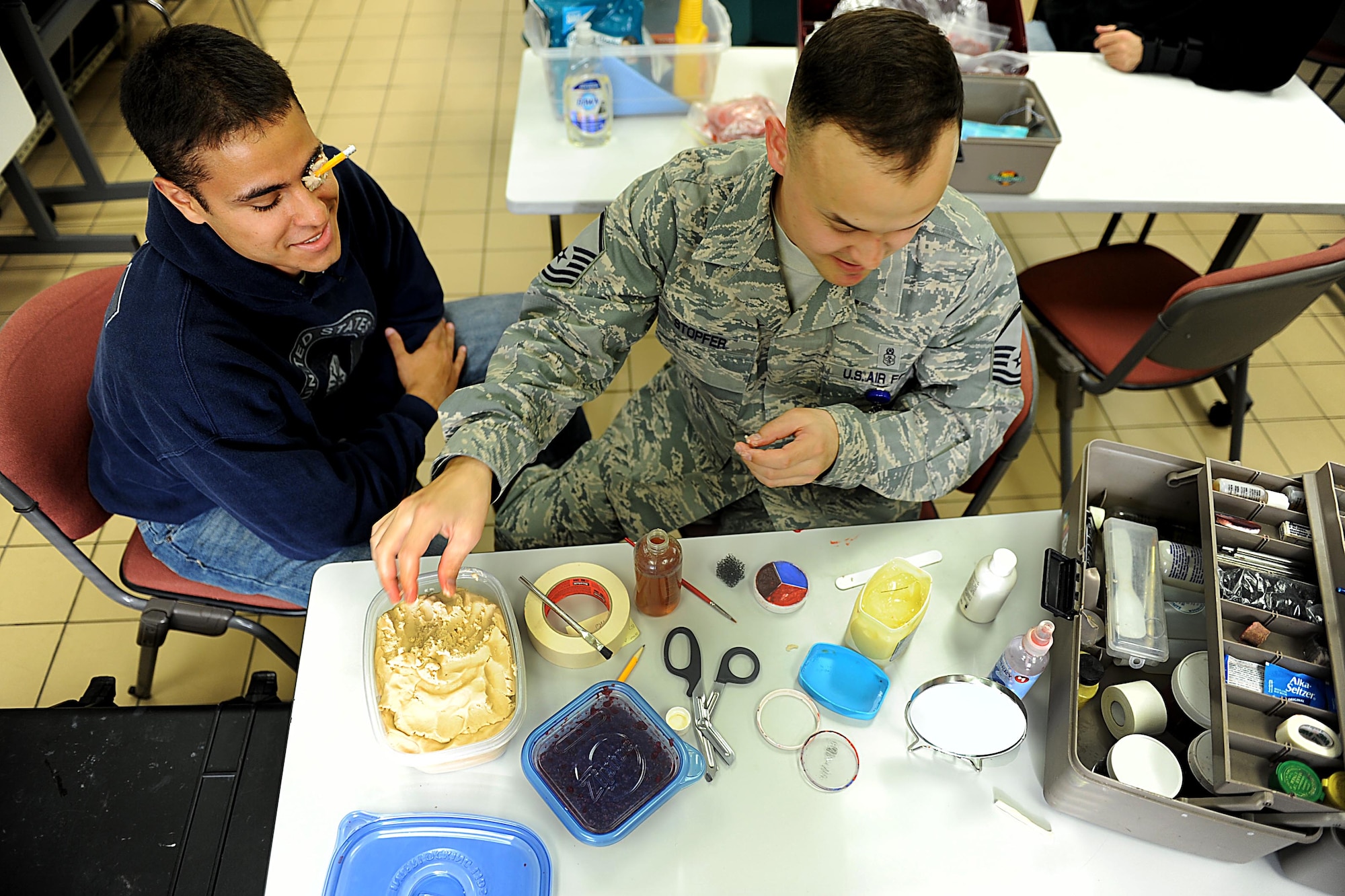 U.S. Air Force Master Sgt. Nicholaus Stopfer, NCOIC of Kadena's area dental laboratory and Senior Airman Anthony Augustine, member of the 961st Airborn Air Control Squadron, laugh as Augustine goes under the transformation to become a victim of "horse play" on Kadena Air Base, March 12, 2012. Kadena is participating in a local operational readiness exercise to prepare Shogun Airmen for possible real world contingencies. (U.S. Air Force photo by Airman 1st Class Brooke P. Beers/Released)