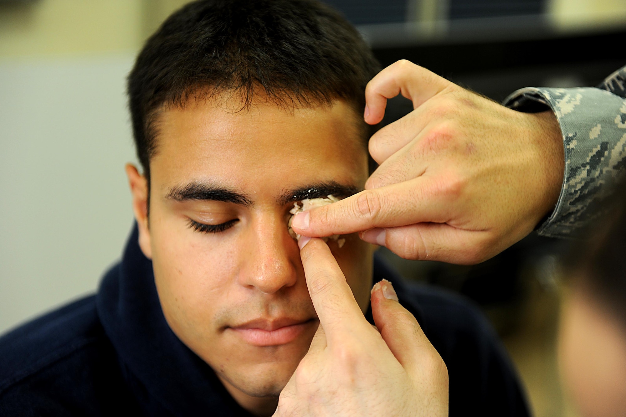 U.S. Air Force Senior Airman Anthony Augustine, member of the 961st Airborn Air Control Squadron, has stage makeup applied to his eye so that he can have fellow Airman practice self aid and buddy care on Kadena Air Base, March 12, 2012. (U.S. Air Force photo by Airman 1st Class Brooke P. Beers/Released)