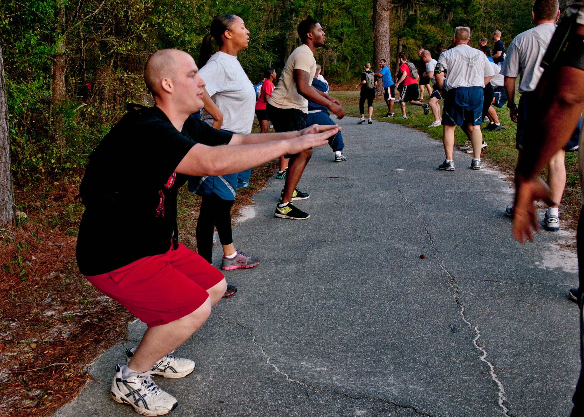 Participants of the Senior Airman Jason D. Cunningham Memorial 10K Workout complete squats at a workout station while running on a jogging trail March  9, 2012, at Moody Air Force Base, Ga. The event was hosted by members of the Airman Leadership School to pay tribute to the 10-year anniversary of the young pararescueman’s death in Afghanistan. With a total of 10 stations, each had a different workout where 26 repetitions were done to honor the age of Cunningham when he passed away. (U.S. Air Force photo by Senior Airman Eileen Meier/Released)