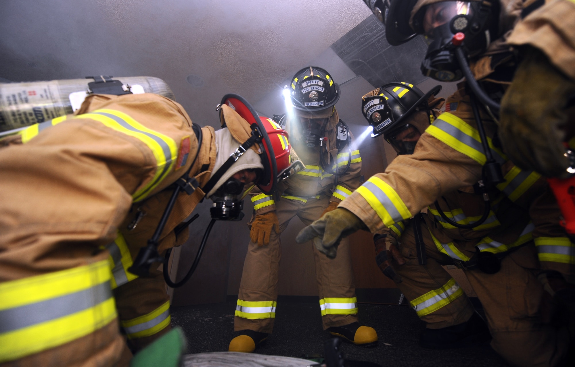U.S. Air Force Brig. Gen. Donald Bacon (middle), 55th Wing commander, watches as a firefighter gets the hose prepared as smoke quickly descends on them from the ceiling as part of a training exercise located in the vacant McCoy Hall at Offutt Air Force Base, Neb., March 7.  The training allowed Bacon to experience the firefighter's rigorous training and witness the firefighters in action.  (U.S. Air Force photo by Josh Plueger/Released).