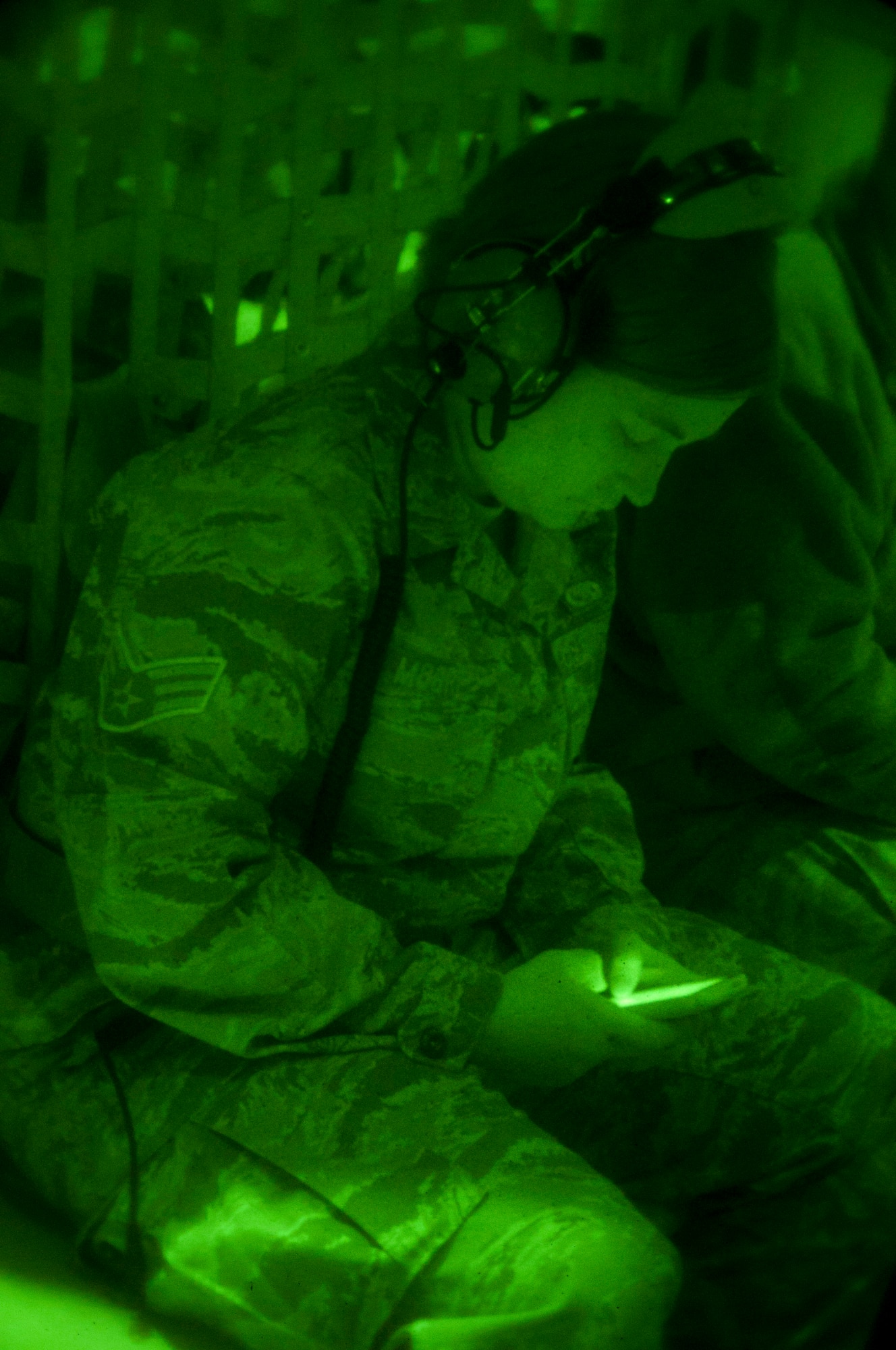 Seen through a night vision lens in the dark cargo area aboard a 133rd Airlift Wing C-130 “Hercules,” an Airman takes a last check on her phone prior to deploying to Afghanistan in support of Operation Enduring Freedom on Mar. 11, 2012. Over thirty members of the 133rd Airlift Wing launched before dawn from the Minneapolis – St. Paul international airport.  USAF official photo by Tech. Sgt. Erik Gudmundson