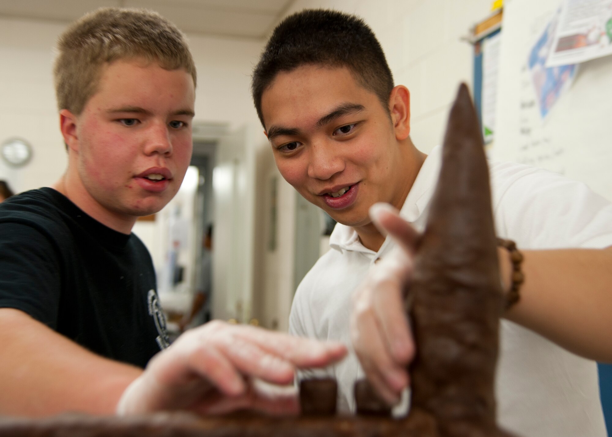 Adam Eudy, left, and Senior Airman Axl Fallesgon, 633rd Force Support Squadron chef, tweak the design for the Joint Base Langley-Eustis Culinary Arts Team showpiece during the 37th Annual Military Culinary Arts Competition at the Joint Culinary Center of Excellence Mar. 5. Adam, a 16-year-old student from South Carolina, was there to work hand-in-hand with the military team. (U.S. Air Force photo by Senior Airman John Strong/Released)