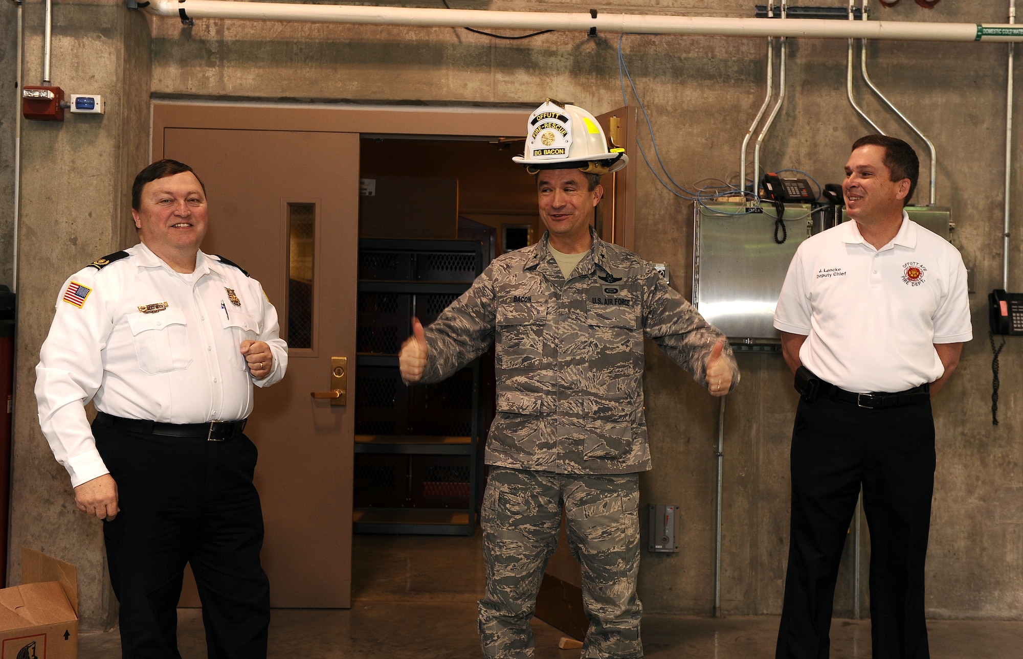 U.S. Air Force Brig Gen. Donald Bacon, 55th Wing commander, gives two thumbs up after receiving his honorary fireman's hat during morning roll call at the firehouse on Offutt Air Force Base, Neb., March 8.  Offutt Fire Chief David Eblin (left) and deputy fire chief James Lencke (right) honored the wing commander with a gift following his 24-hour shift he spent with Offutt's fire fighters.  (U.S. Air Force photo by Josh Plueger/Released).