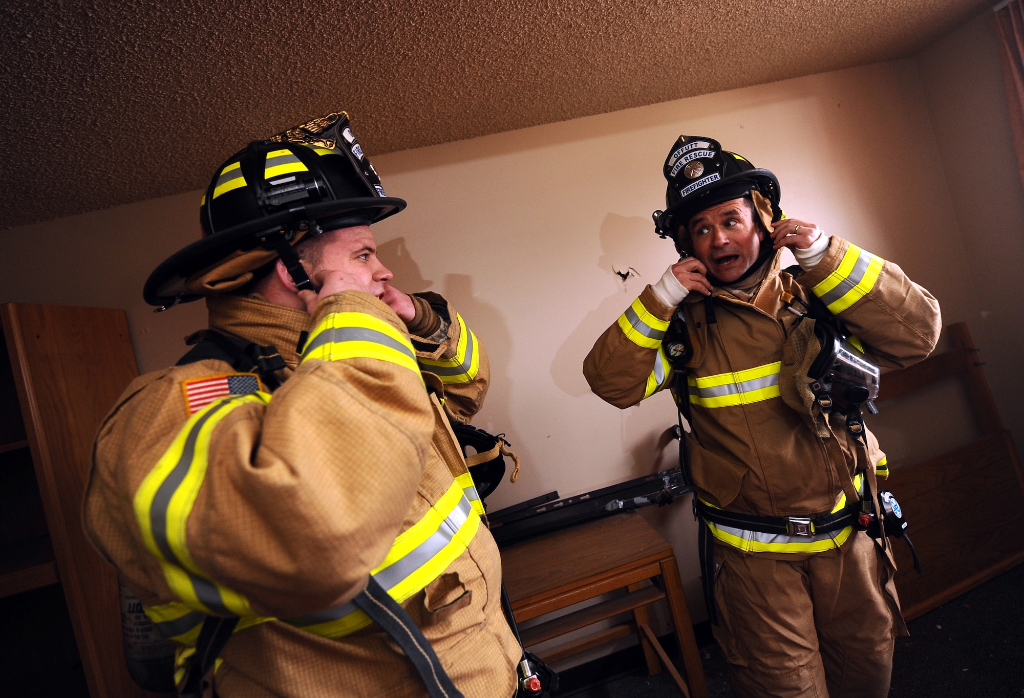 Lucas Lechtenberg, Offutt Air Force Base firefighter, removes his protective gear as does U.S. Air Force Brig. Gen. Donald Bacon, following a fast paced training session that involved storming McCoy Hall to find "dummies" representing survivors in the room at Offutt Air Force Base, Neb., March 7.  Bacon spent 24 hours with Offutt firefighters, training, eating and sleeping in the bunks to gain perspective for how their life is spent on base and in the firehouse.  (U.S. Air Force photo by Josh Plueger/Released).