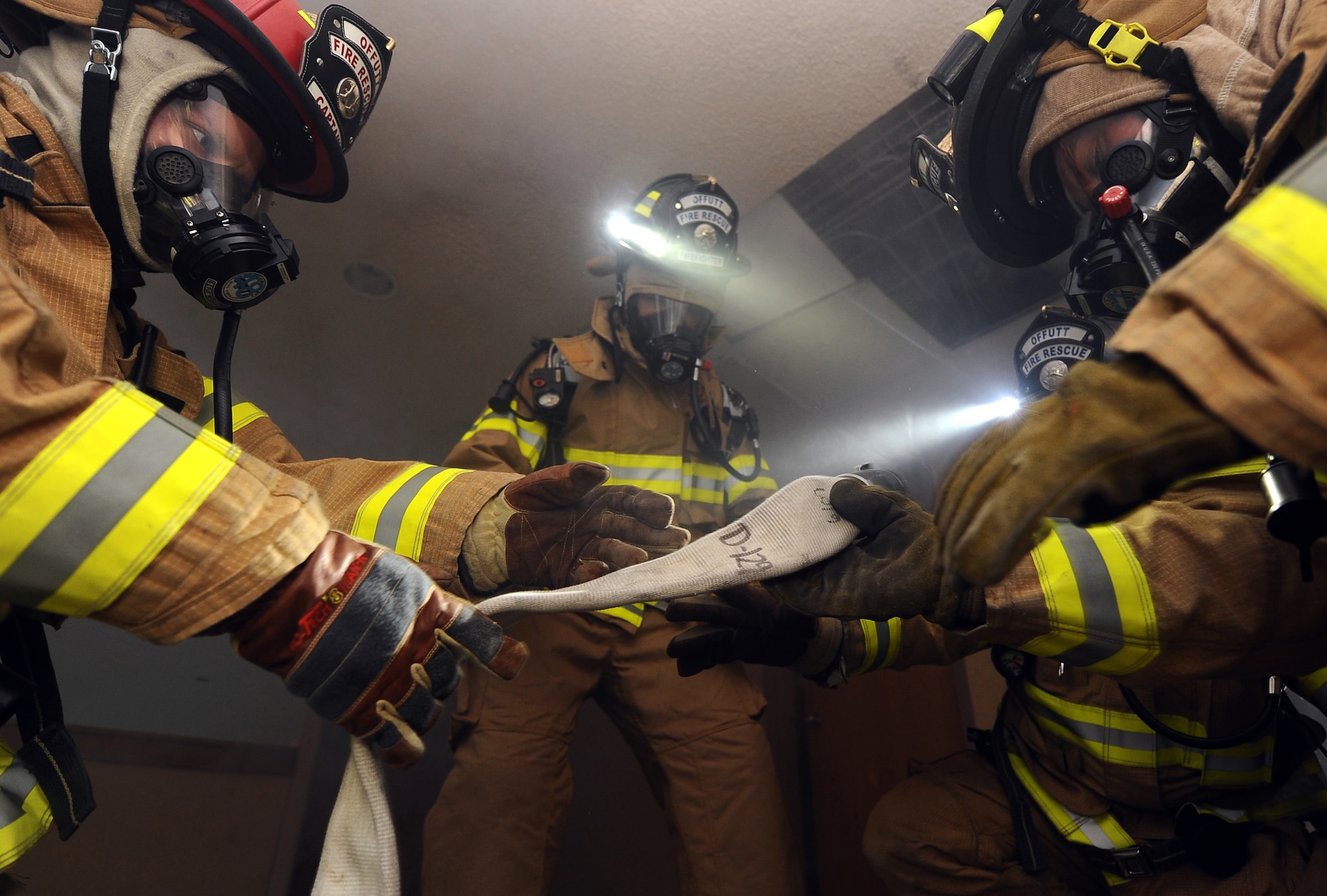 U.S. Air Force Brig. Gen. Donald Bacon (middle), 55th Wing commander, watches as firefighters prepare the hose as smoke quickly descends on them from the ceiling as part of a training exercise located in McCoy Hall at Offutt Air Force Base, Neb., March 7.  The training gave Bacon a front row seat to see the firefighters in action.  (U.S. Air Force photo by Josh Plueger/Released).