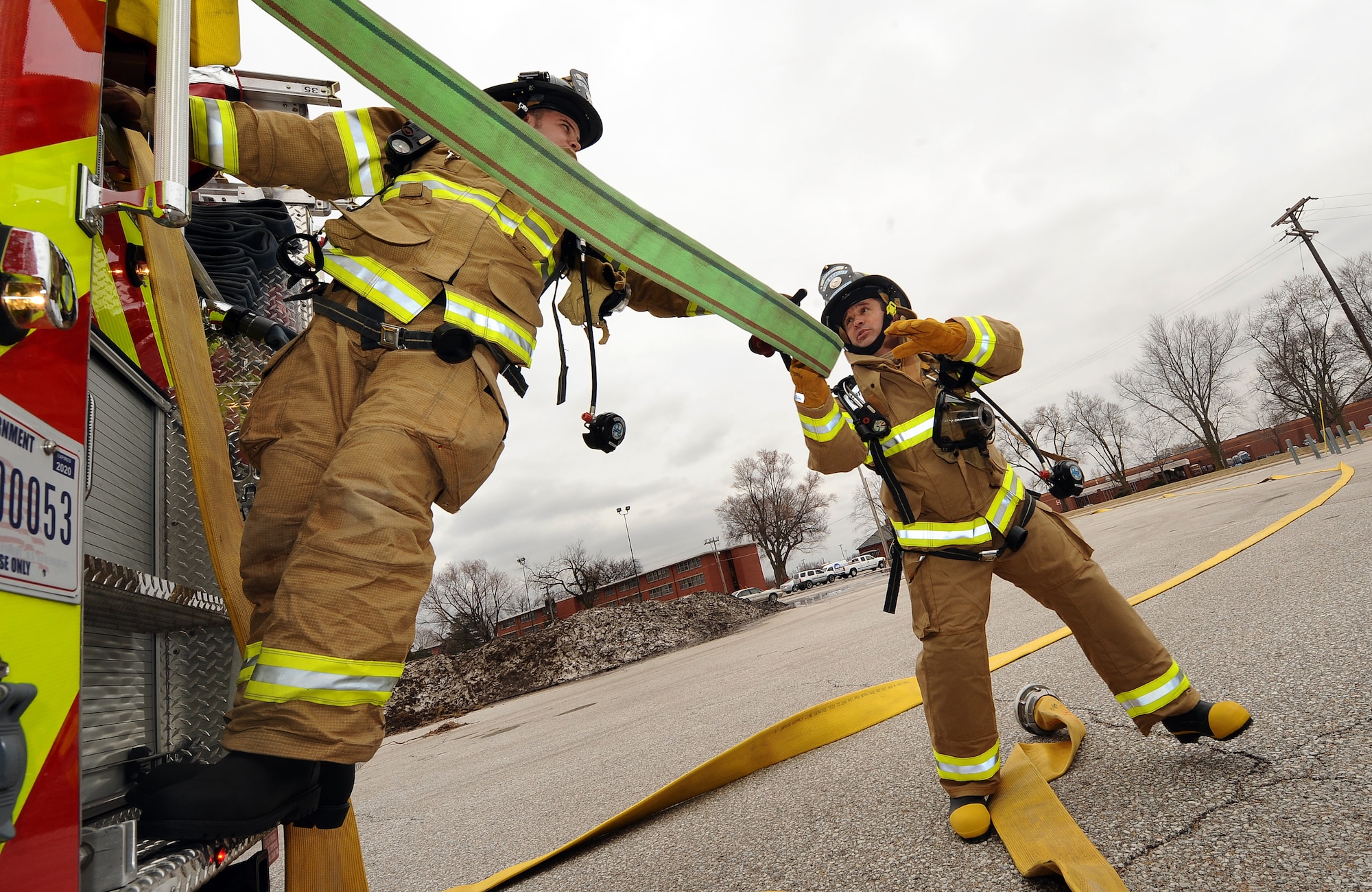 Lucas Lechtenberg, Offutt Air Force Base firefighter, unravels a hose from a fire truck as U.S. Air Force Brig. Gen. Donald Bacon, 55th Wing commander, takes the hose seconds before entering a mock fire inside of the McCoy Hall, an empty dorm building at Offutt AFB, Neb., March 7.  Bacon spent a 24-hour period with Offutt firefighters to get an up-close look into their operations and life in the firehouse.  (U.S. Air Force photo by Josh Plueger/Released).
