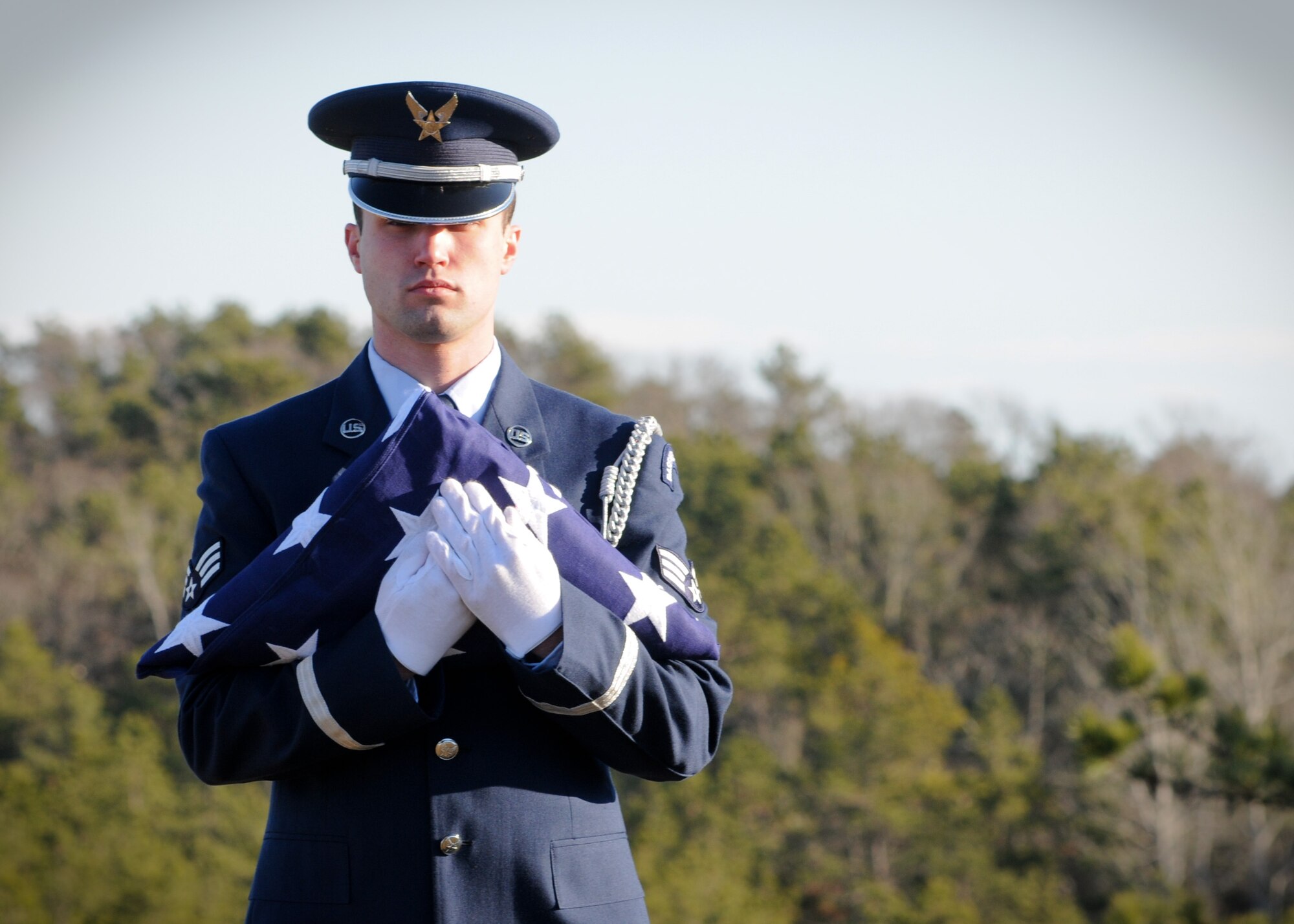 Senior Airman Zackery Benton of the 102nd Honor Guard prepares to unfold a flag in honor of a fallen veteran at the Bourne National Cemetery Jan. 19. (National Guard photo by Tech. Sgt. Kerri Cole/Released)