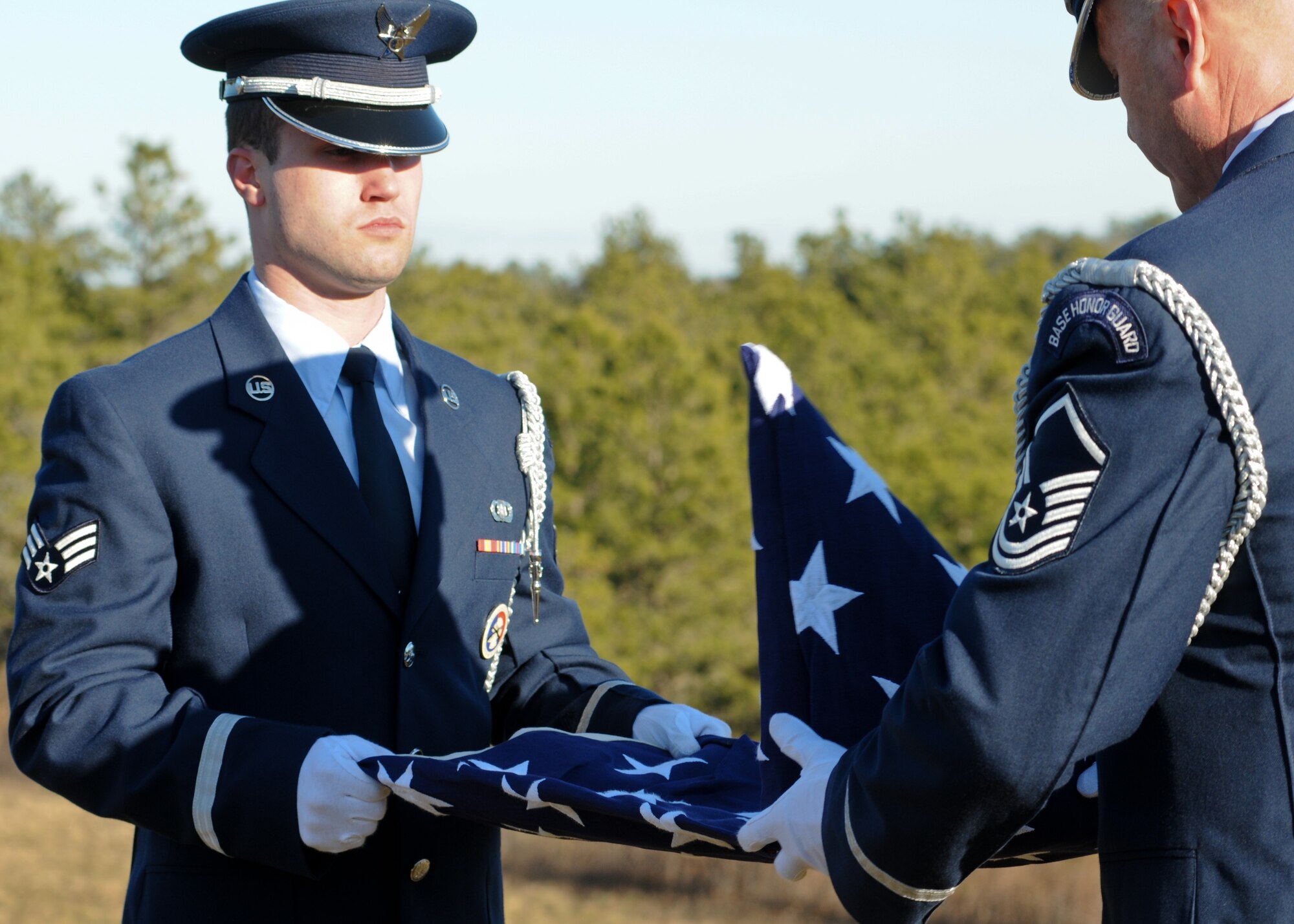 Senior Airman Zackery Benton of the 102nd Honor Guard prepares to unfold a flag in honor of a fallen veteran at the Bourne National Cemetery Jan. 19. (National Guard photo by Tech. Sgt. Kerri Cole/Released)