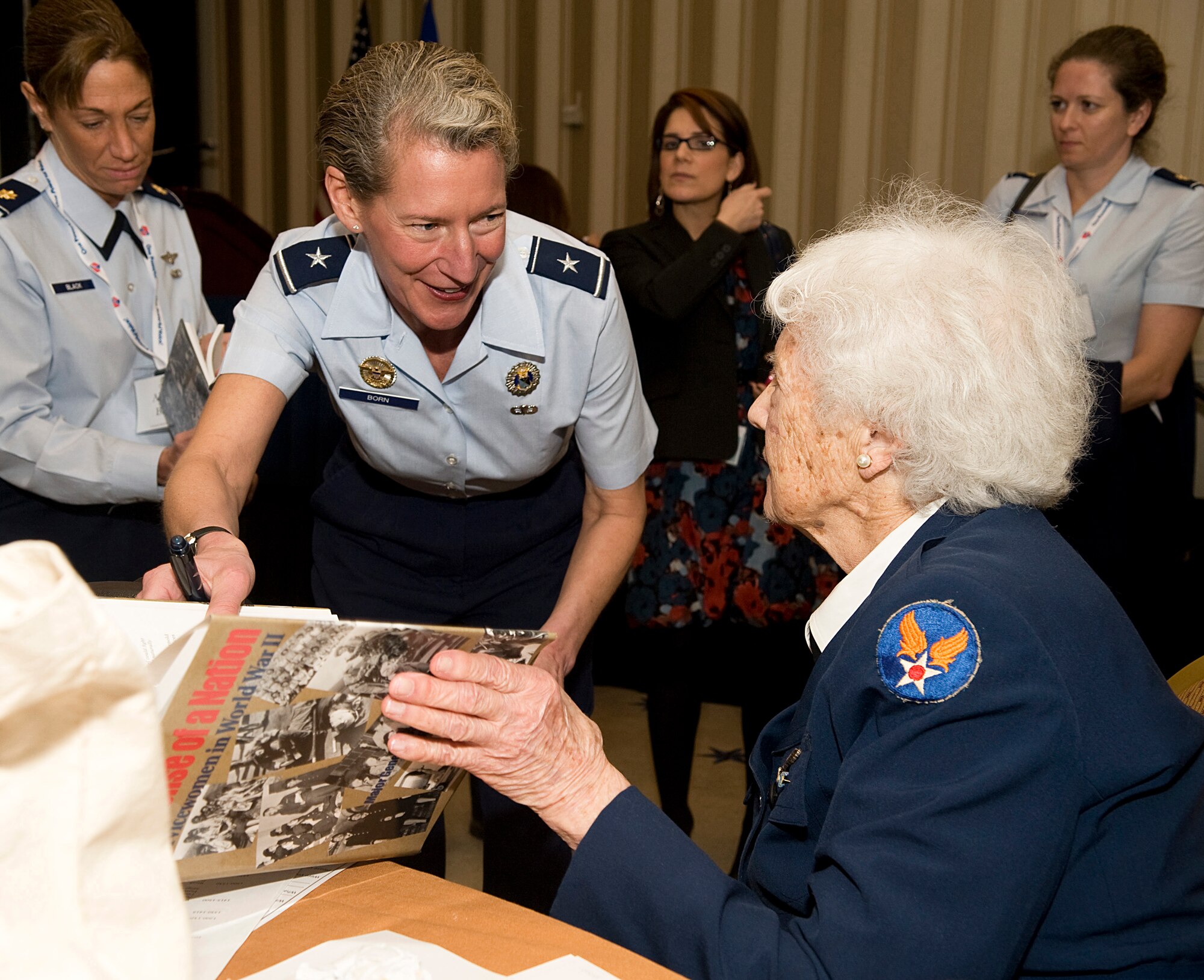 Elaine Harmon, right, one of the Women Airforce Service Pilots of World War II, autographs a book for Brig. Gen. Dana Born during the Joint Women's Leadership Symposium Mar. 6, 2012, at the National Harbor in Washington, D.C. This event offered more than 1,700 women from all Service branches the opportunity to focus on professional and leadership development. (U.S. Air Force photo by Master Sgt. Jeanette Spain)