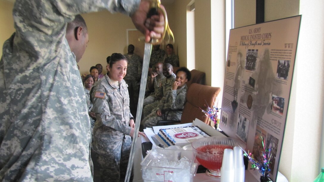 U.S. Army 1st Sgt. Damon T. Clark unsheathes the noncommissioned officer sword that he and Pfc. Gloria M. Najera used to cut the anniversary cake marking the 125th anniversary of the Medical Enlisted Corps observance at Fort Eustis, Va., Mar. 1.  Both assigned to the Medical Company of McDonald Army Health Center, Clark and Najera were honored as the youngest and oldest Soldier present.   (U.S. Army photo by Marlon Martin/Released)