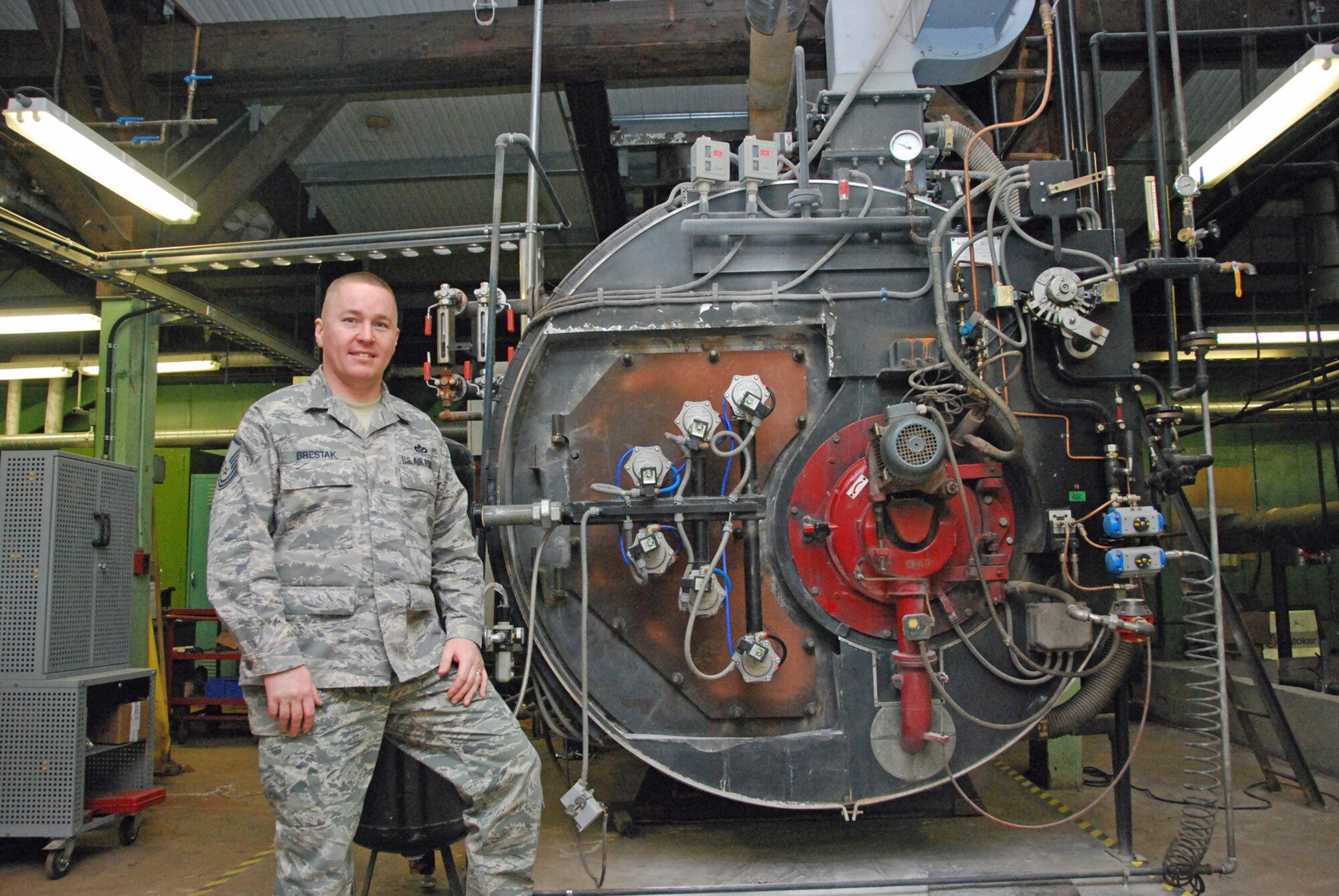 Master Sgt. Peter Brestak, 821st Support Squadron, stands next to a rotary fuel burner that engineers retrofitted to burn waste JP-8 and reclaimed petroleum lubricants. By burning waste JP-8 and petroleum products, the engineers were able to save the Air Force more than $200,000 per year in fuel costs alone. (U.S. Air Force photo/Senior Airman Zhenhua Xie)