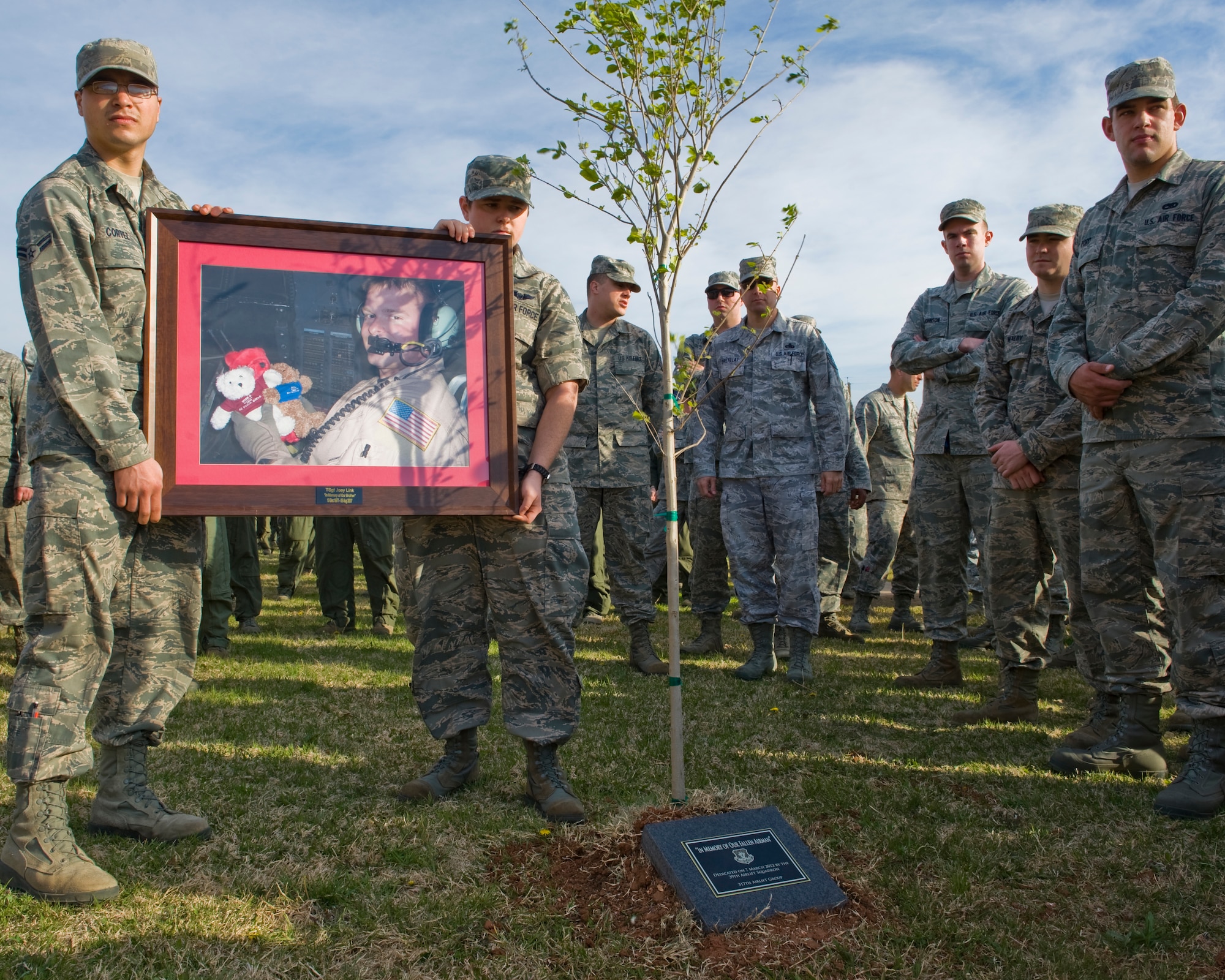U.S. Air Force Airman 1st Class Marcus Cortez, left, and Senior Airman Elizabeth Patton, right, hold a photo of Tech. Sgt. Joey Link, 39th Airlift Squadron, during a memorial service March 7, 2012, at Dyess Air Force Base, Texas. A memorial service was held for Tech. Sgt. Link who died of natural causes during a deployment in Southwest Asia. (U.S. Air Force photo by Airman 1st Class Jonathan Stefanko/ Released)