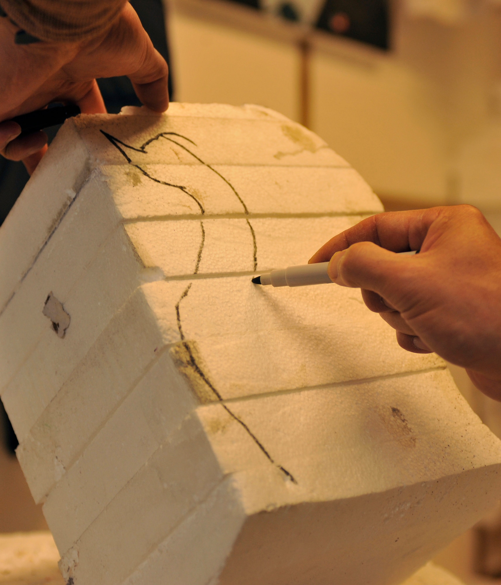 BAGRAM AIRFIELD, Afghanistan-- Euigang Jung outlines the shape of a swan on packaging styrofoam at Bagram Airfield, Afghanistan, Feb. 14, 2012. Jung is a decoration designer with Fluor, a service and construction engineering company, and works at the Dragon Dining Facility building decorations out of recycled styrofoam. (U.S. Air Force photo/Airman 1st Class Ericka Engblom)