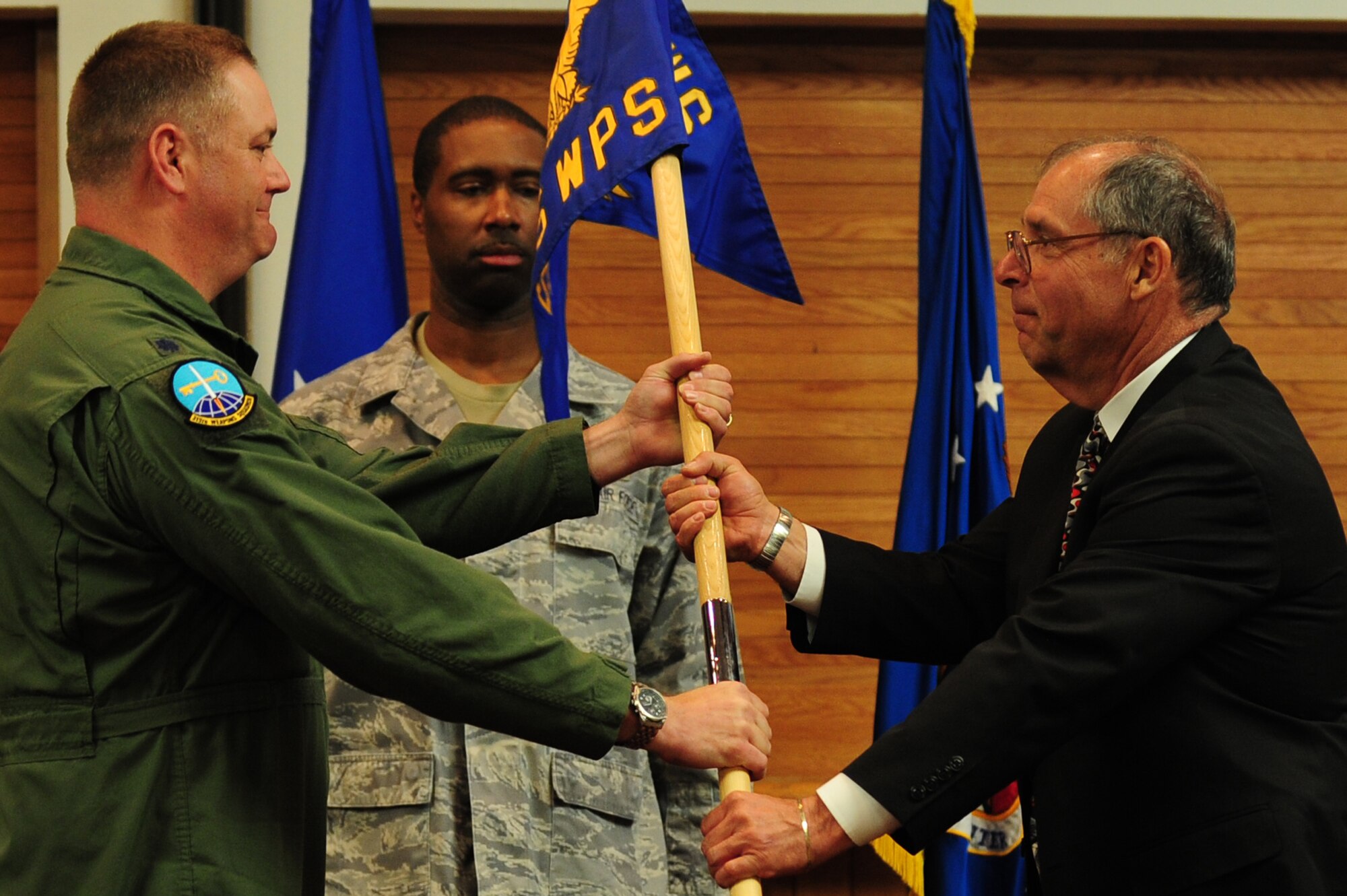 U.S. Air Force Lt. Col. Jason Seyer, 315th Weapons Squadron commander, passes the guidon to Dennis Soukup, department chair of Applied Technologies at the College of Southern Nevada, during a commander's call at Nellis Air Force Base, March 9, 2012.  A total of eleven new honorary commanders assumed command during the induction.  (U.S. Air Force photo by Staff Sgt. William P.Coleman)