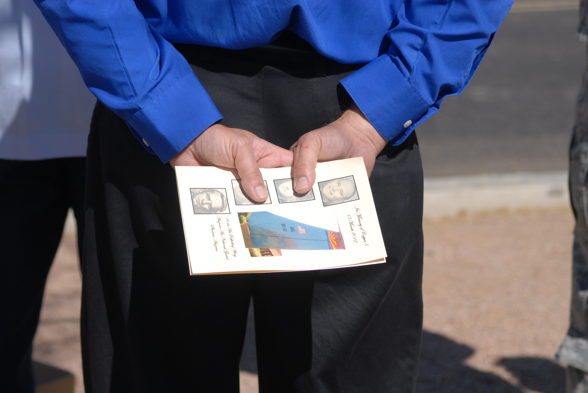 A guest holds a memorial program while listening to dedicatory remarks during a memorial ceremony dedicating a KC-135 Stratotanker tail and plaque March 13, 2012, at the 161st Air Refueling Wing, Phoenix. The memorial ceremony marked the 30th anniversary when four 161st Air Refueling Group servicemembers lost their lives while on-duty. (Photo by Master Sgt. Robert Storm/Released)