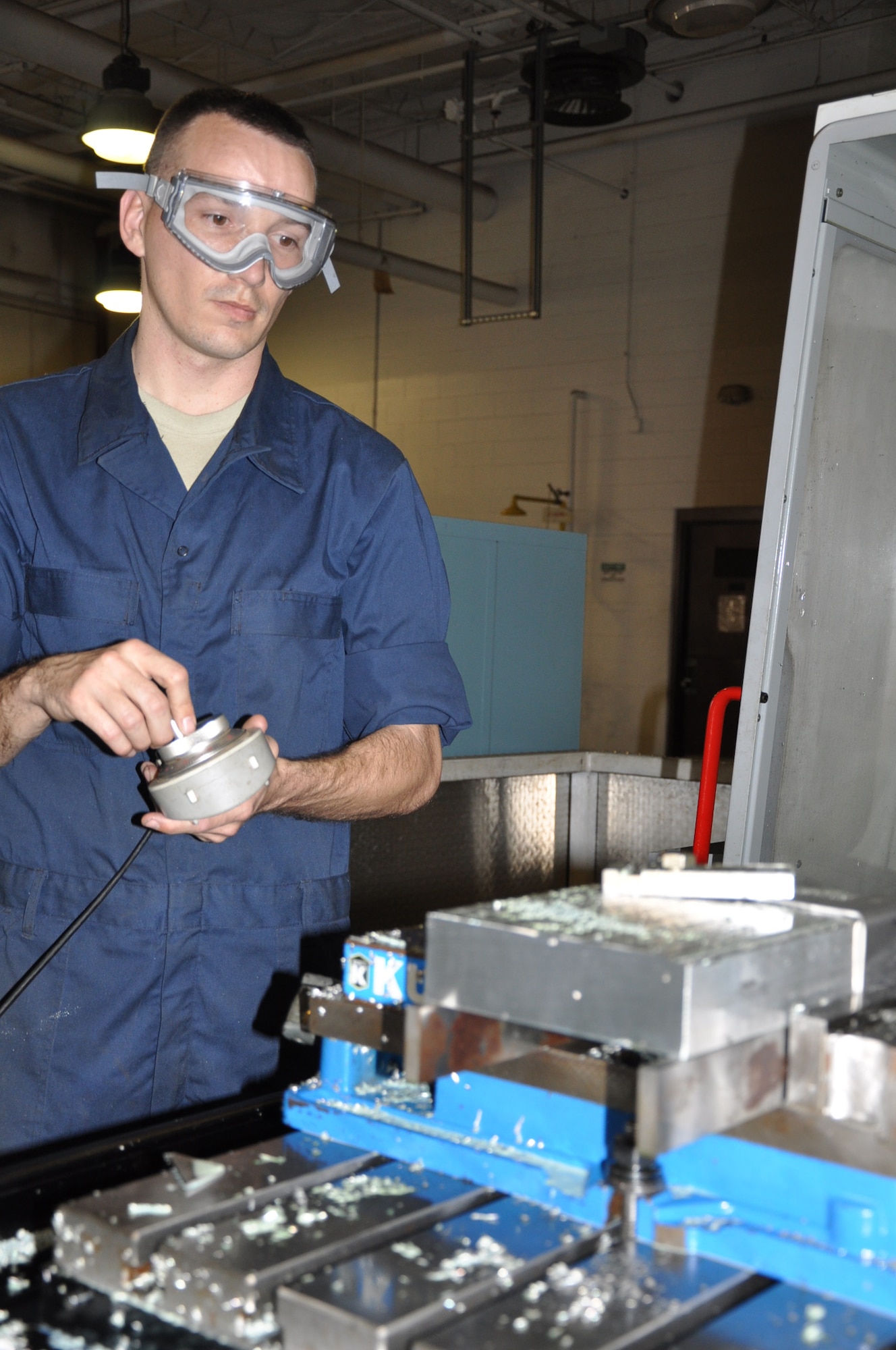 Staff Sgt. Charles King, metals technologist, 931st Maintenance Squadron, uses a remote to move the table of a computer numerical control, after machining a corner brace for an aircraft galley. The Metals Technology section is comprised of a Total Force Iniative staff of 16 active duty airmen from the 22nd Maintenance Squadron, one Air Reserve Technician and two Reservists from the 931st Maintenance Squadron. The CNC can be programmed to machine parts or equipment. (Air Force photo by Tech. Sgt. Brannen Parrish) 