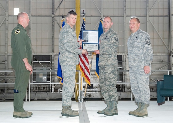 Maj. Anthony Antoline, 412th Aircraft Maintenance Squadron commander (left) presents Staff Sgt. Derick Duback, 445th Aircraft Maintenance Unit, with a certificate at the Dedicated Crew Chief Ceremony March 5 as Brig. Gen. Robert C. Nolan II, Air Force Flight Test Center commander and Chief Master Donald Miles (right), 412th Maintenance Group, look on. (Air Force Photo by Rob Densmore)