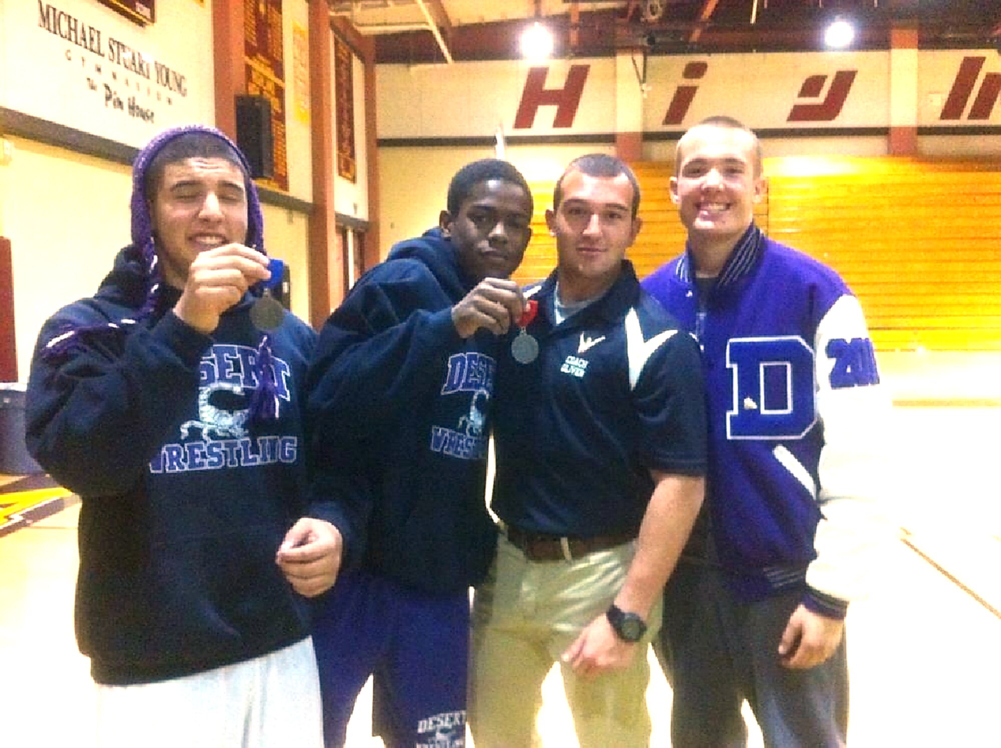 Senior Airman Steven Oliver, 412th Maintenance Group, Weapons Load Crew team member (second from right), poses with members of the Desert High School Wrestling Team. Oliver is the wrestling coach at the base's high school and is this week's Warrior of the Week. (Courtesy photo)