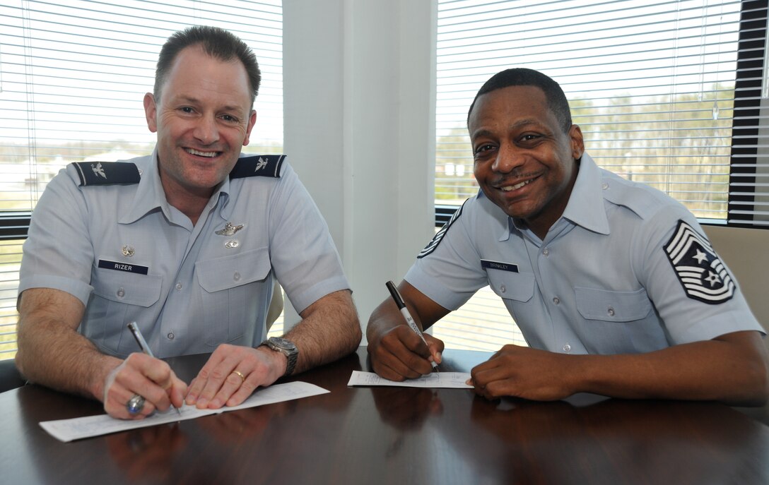 Col. Ken Rizer, 11th Wing/Joint Base Andrews commander and Chief Master Sgt. Anthony Brinkley, 11 WG/Joint Base Andrews command chief, kick off Andrews’ Air Force Assistance Fund campaign by each signing an Air Force Form 2561, the official AFAF donation form. (U.S. Air Force photo/Airman 1st Class Lindsey A. Beadle) 