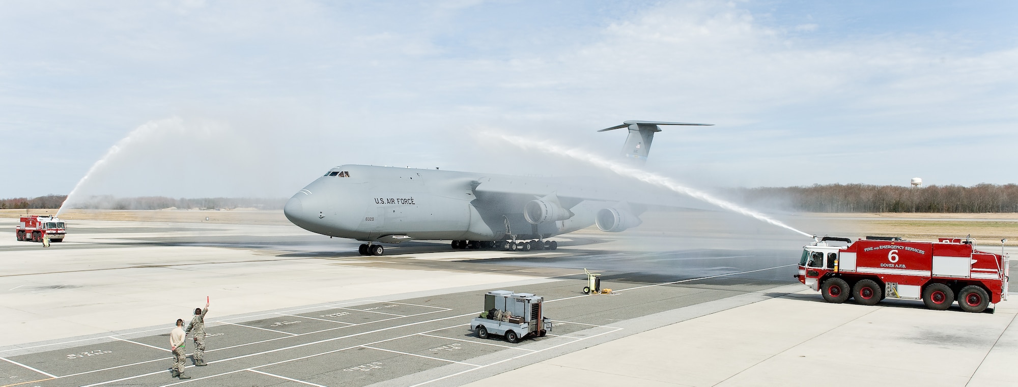 Firetrucks from the 436th Civil Engineer Squadron Fire Department give C-5B Galaxy 86-0020 and aircrew a customary spray-down as it pulls into its parking spot following its “fini flight” March 12, 2012, at Dover Air Force Base, Del. The 9th Airlift Squadron now exclusively employs the C-5M Super Galaxy for local training, and state-side and overseas missions. (U.S. Air Force photo by Roland Balik)