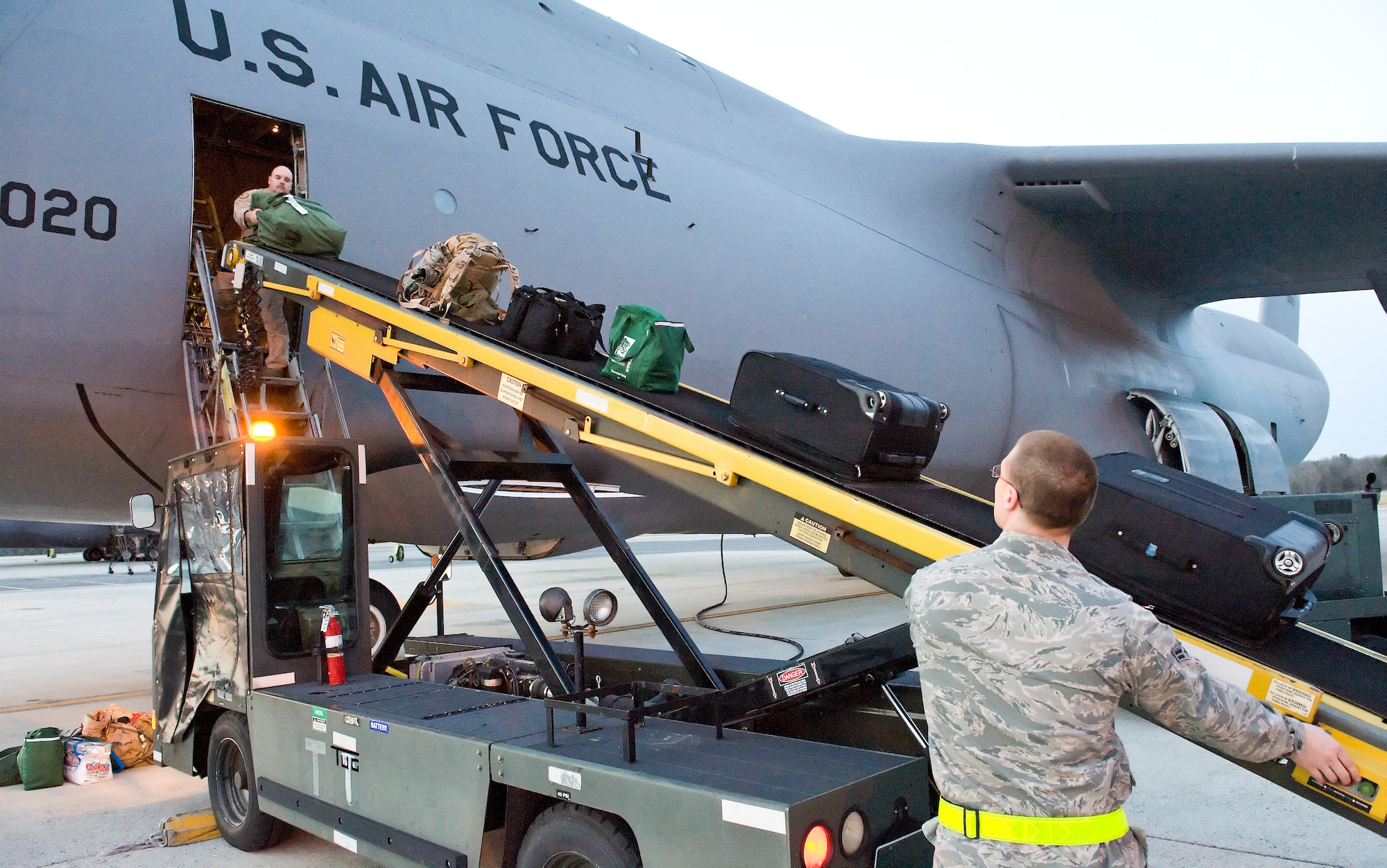 Airman 1st Class Khristian Thompson, right, jetside services specialist with the 436th Operations Support Squadron, sends baggage up the conveyor to Tech. Sgt. Ronald Reazor, a loadmaster with the 9th Airlift Squadron, March 8, 2012, at Dover Air Force Base, Del. The 9th Airlift Squadron now exclusively employs the C-5M Super Galaxy for local training, and state-side and overseas missions. (U.S. Air Force photo by Roland Balik)