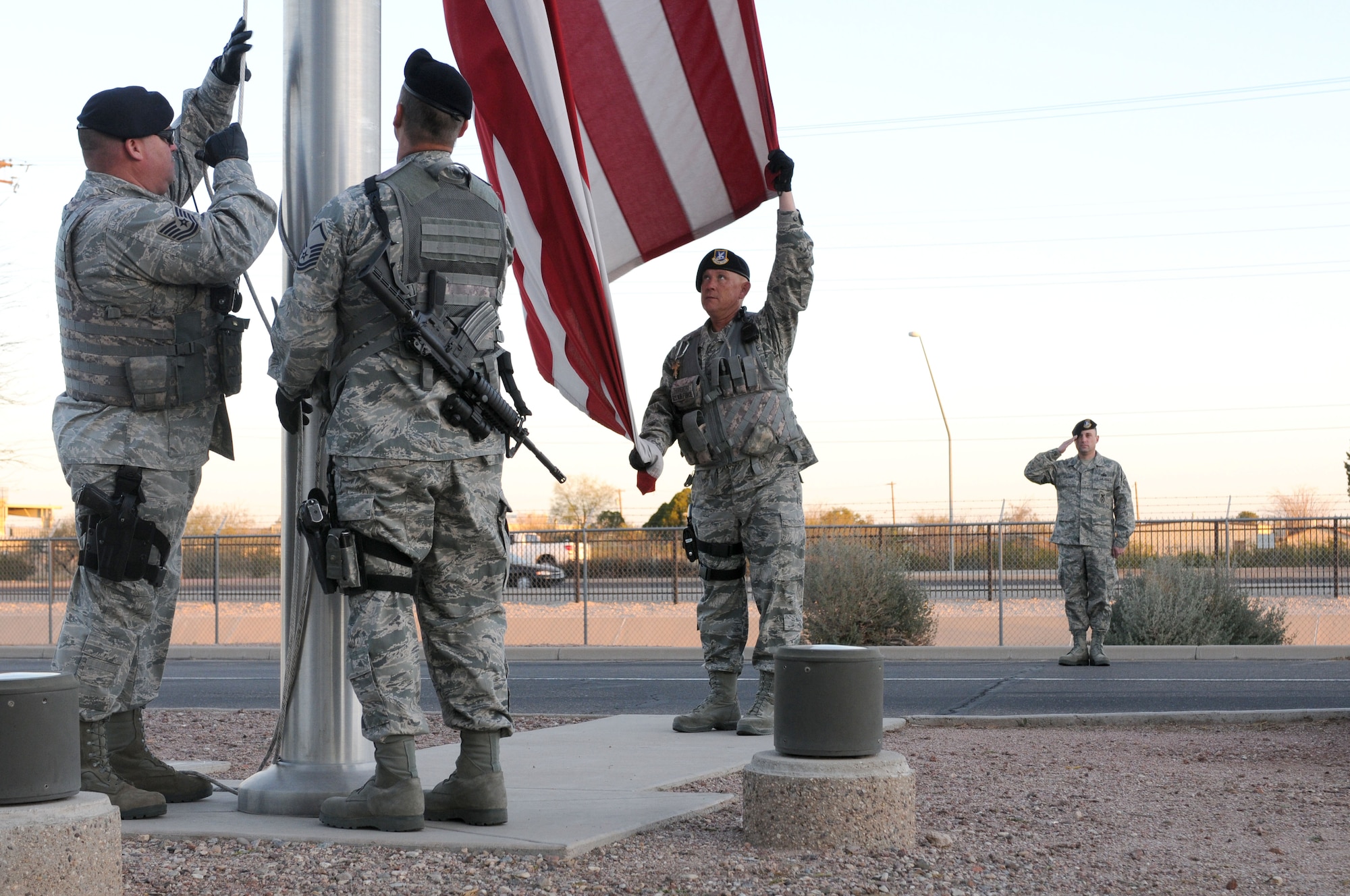 Tech. Sgt. Michael Royval, Master Sgt. Vince Muskiet and Master Sgt. Jeff Thornsberry raise the U.S. flag Feb. 27 at the 162nd Fighter Wing at Tucson International Airport while Master Sgt. James Mulcahey salutes. Even if the National Anthem isn’t played, Airmen on base are reminded to stop and salute if they see this ceremony occurring on base and drivers are reminded to pull over and stop until it’s completed. (U.S. Air Force photo/Maj. Gabe Johnson)