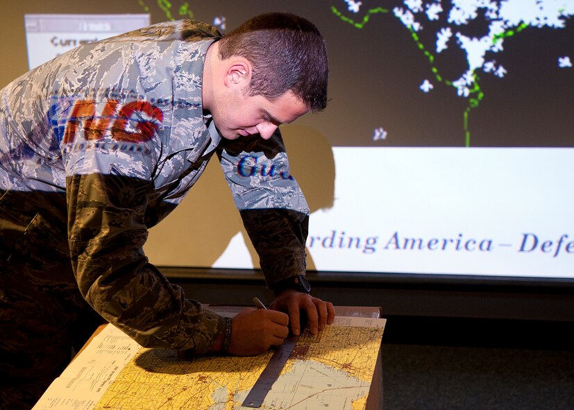 Senior Airman Matthew Sprockett, an intelligence analyst with the 180th Fighter Wing, Ohio Air National Guard, Swanton, Ohio demonstrates proper map plotting techniques prior to an F-16 training mission Dec. 20. Map plotting improves situational awareness for aircrew members for training and real-world missions.