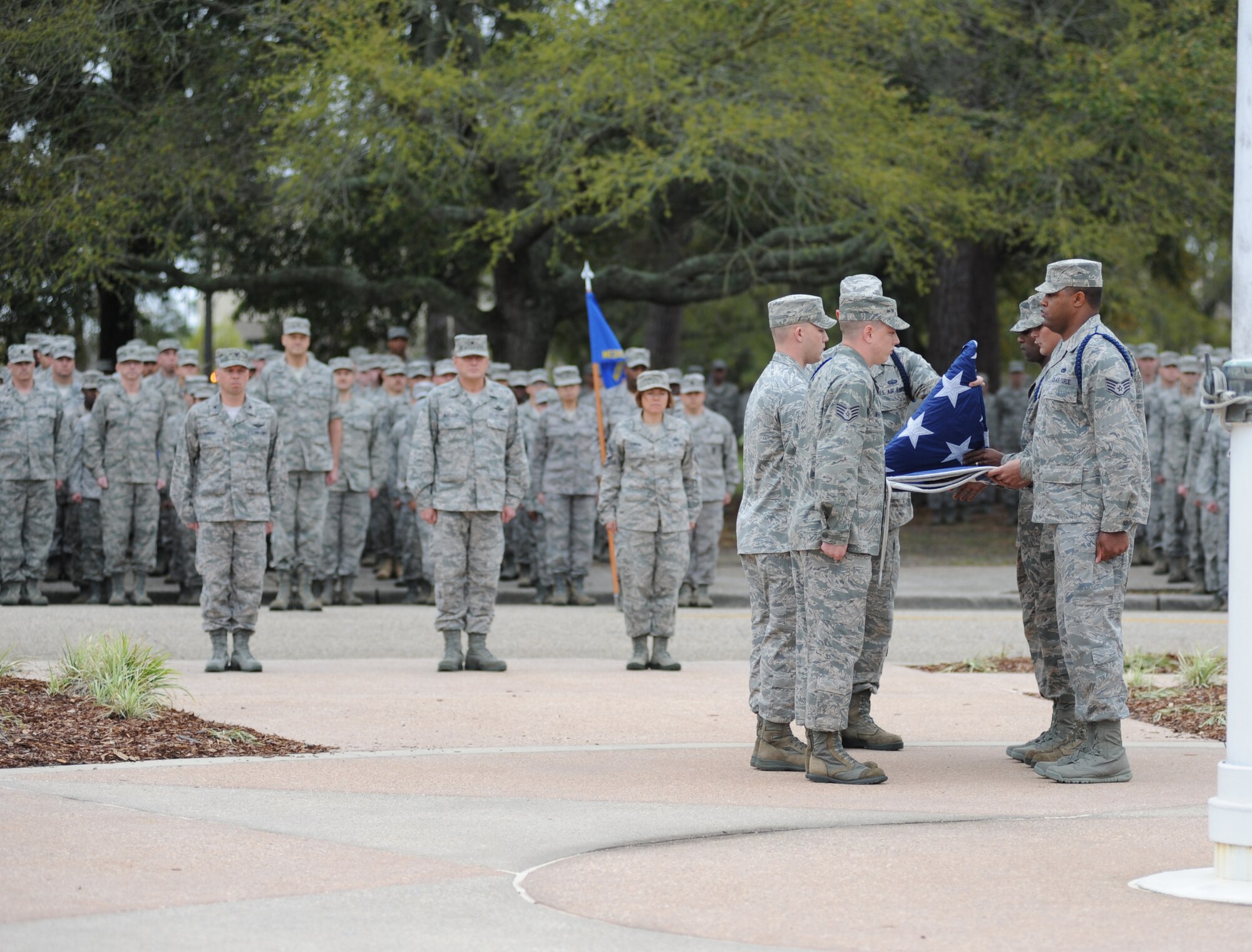 Military Training Leaders serving as the flag detail complete the flag folding while flights from the 81st Mission Support Group,  81st Training Group, and 81st Medical Group, stand at attention during the 81st Training Wing retreat ceremony March 9, 2012, Keesler Air Force Base, Miss.  (U.S. Air Force photo by Kemberly Groue)