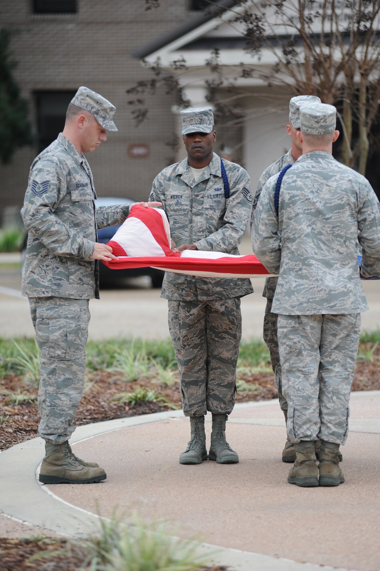 Tech. Sgt. Daniel Schumann, 335th Training Squadron; Staff Sgt. Nicholas Wilson, 81st Training Group; and Staff Sgt. Brandon Barrette, 335th TRS, perform a flag folding ceremony during the 81st Training Wing retreat ceremony March 9, 2012, Keesler Air Force Base, Miss.  (U.S. Air Force photo by Kemberly Groue)