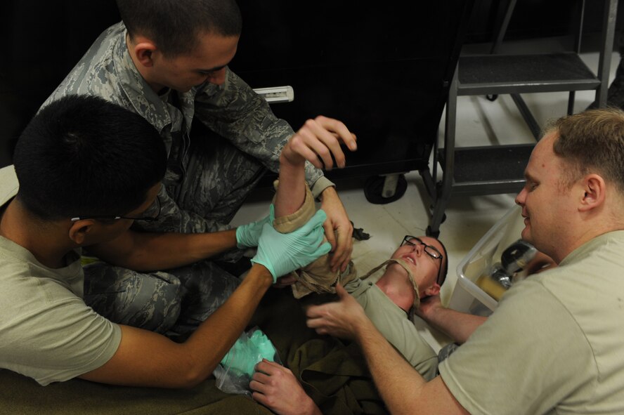 U.S. Air Force Airman 1st Class Francisco Andraca and Cooper Omundson, aerospace propulsion journeymen, from the 18th Component Maintenance Squadron use teamwork to stop the service member’s bleeding arm during a local operational readiness exercise Beverly High 12-3 on Kadena Air Base, Japan, March 13, 2012. LORE scenarios allow Airmen a chance to practice self-aid and buddy care so that they can be ready for different real world contingencies. (U.S. Air Force photo/Airman 1st Class Justin Veazie/Released) 
