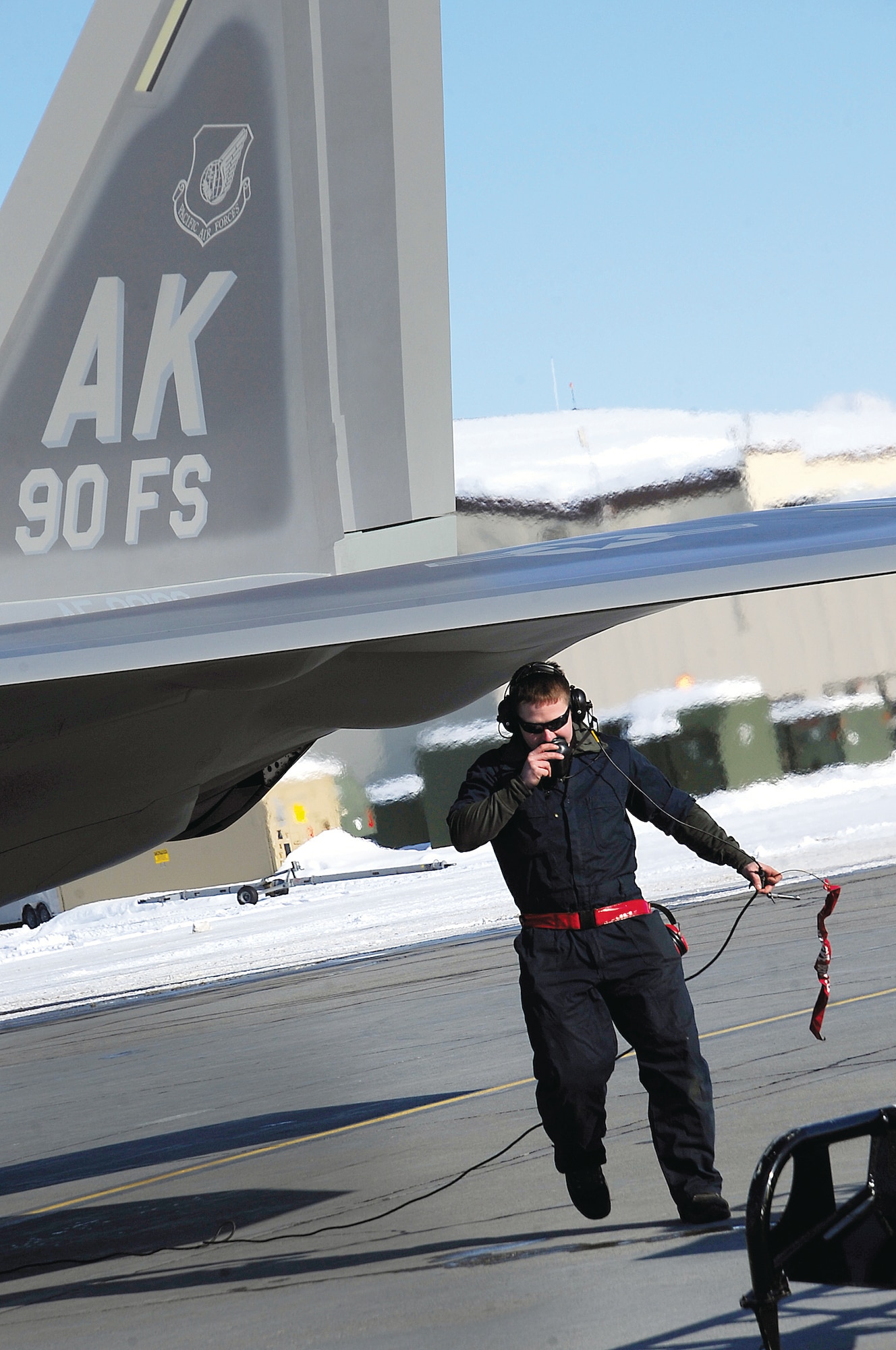 JOINT BASE ELMENDORF-RICHARDSON, Alaska -- Staff Sgt. James Lacina uses the communications system to talk with an F-22 Raptor pilot after it arrived here March 7. The 90th Fighter Squadron received a new F-22 Raptor and recognized it as their squadron's flagship. A flagship is a dedicated aircraft with the squadron's, commander's and dedicated crew chief's names painted on parts of the aircraft. Lacina is the flagship's assigned dedicated crew chief with the 90th Aircraft Maintenance Squadron. (U.S. Air Force photo by Staff Sgt. Cynthia Spalding)