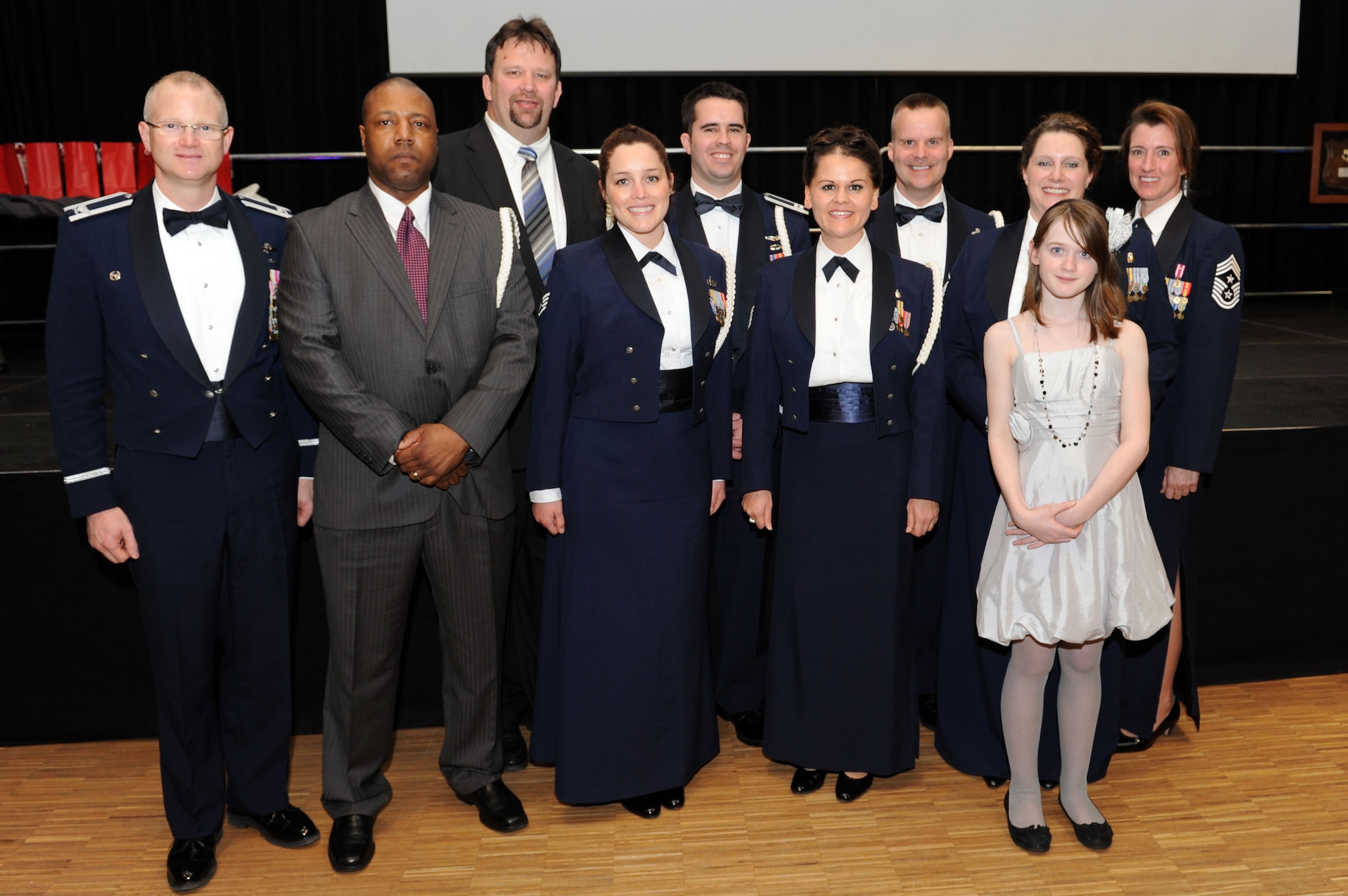 BITBURG, Germany – Col. Christopher Weggeman, 52nd Fighter Wing commander, and Chief Master Sgt. Sandra Miller, 52nd FW command chief, stand with 52nd FW Annual Award winners, front row, Mr. Jeff Caudle, 52nd Mission Support Group, civilian category II of the year; Staff Sgt. Christina Camp, 726th Air Mobility Squadron, volunteer of the year; Tech. Sgt. Ronna Cabello, 52nd Medical Group, NCO of the year; Master Sgt. Lisabeth Jones and Becca Jones, daughter of Senior Master Sgt. Neil Jones, 52nd Civil Engineer Squadron, currently deployed, SNCO of the year. Second row, Mr. John Dymond, 52nd Operations Group, civilian category 1 of the year; Capt. Matthew Orlovsky, 52nd Operations Group, company grade officer of the year; and Senior Master Sgt. Richard Schlosser, 470th Air Base Squadron, first sergeant of the year. A ceremony was held March 9 at Bitburger Stadthalle to recognize all wing nominees and winners. (U.S. Air Force photo by Senior Airman Christopher Toon/Released)