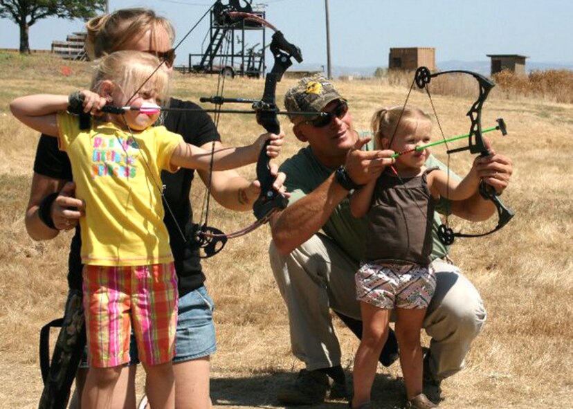(Right) Master Sgt. Chad Hepner, 9th Medical Group first sergeant, and his wife (left) Staff Sgt. Michelle Hepner, 9th Force Support Squadron personnel, work with their daughters on archery skills at the Rod and Gun Club at Beale AFB, Calif. Master Sgt. Hepner has served as a volunteer base game warden at Beale and prior duty stations for 11 years during his career. (U.S. Air Force courtesy photo)